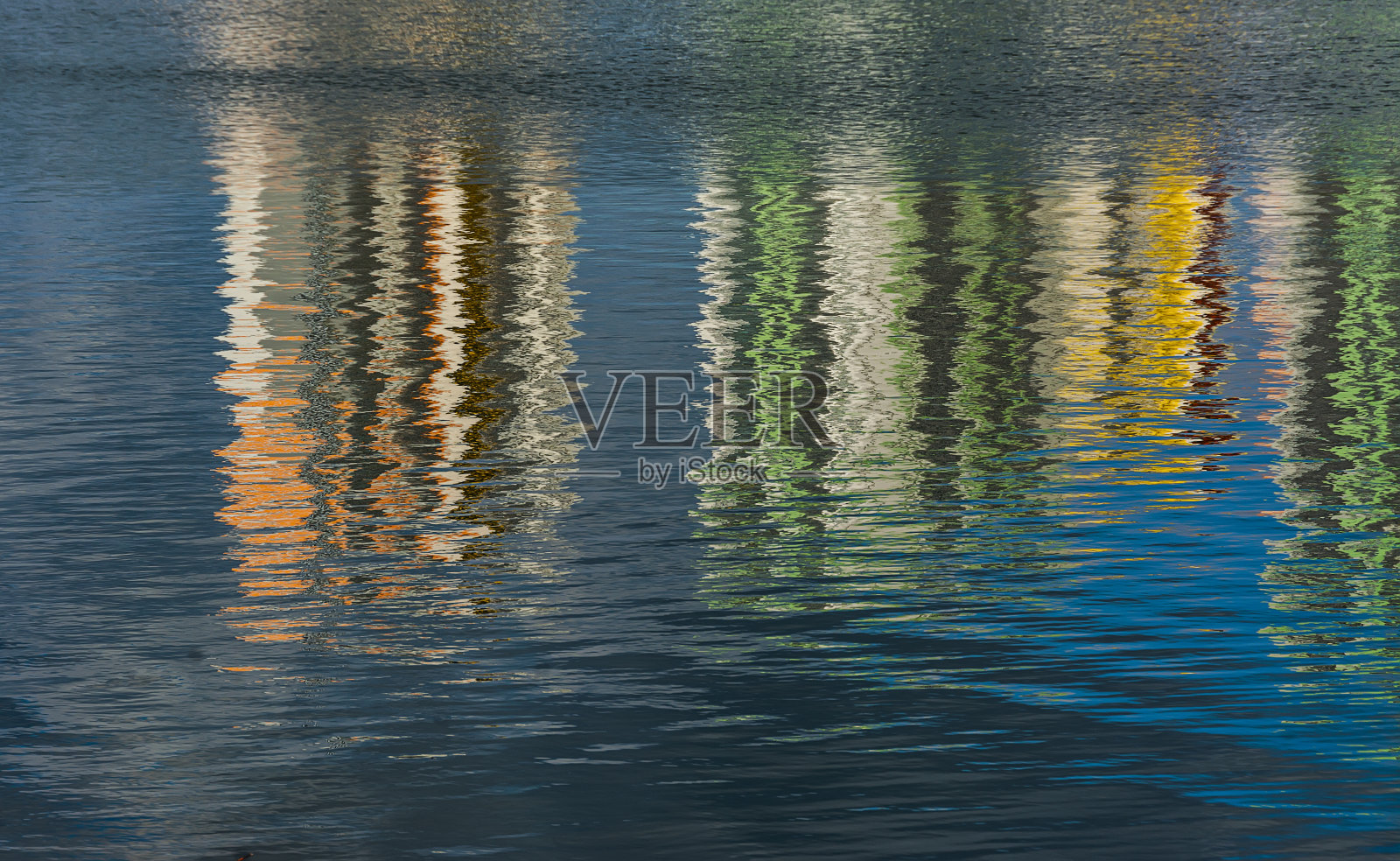 在多风的天气里，池塘的水面上倒影着高楼大厦。照片摄影图片