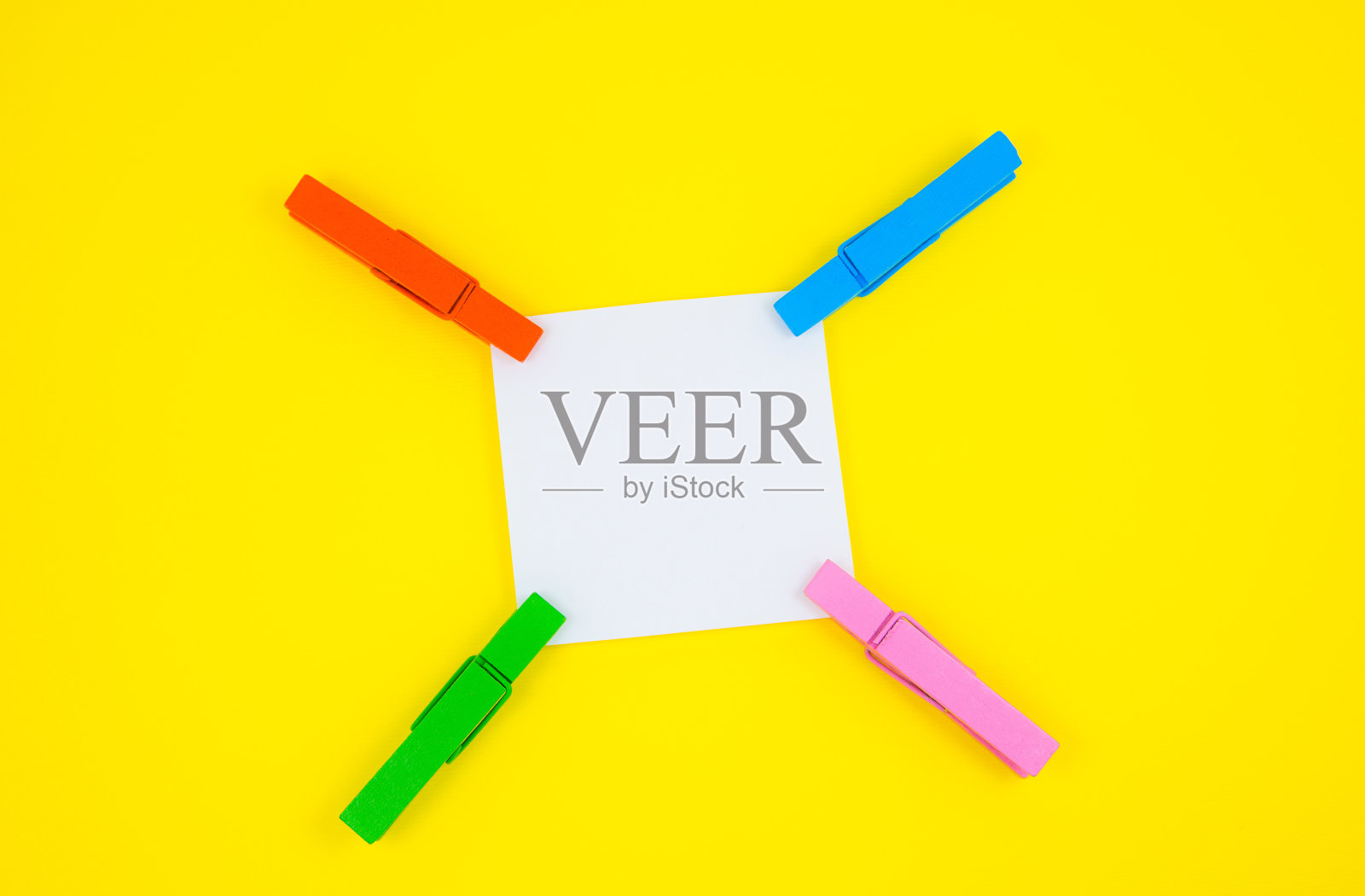 空白白色待办事项贴纸与彩色木制晾衣夹。在黄色背景上关闭提醒纸。副本的空间。极简主义，原创和创意的照片。照片摄影图片