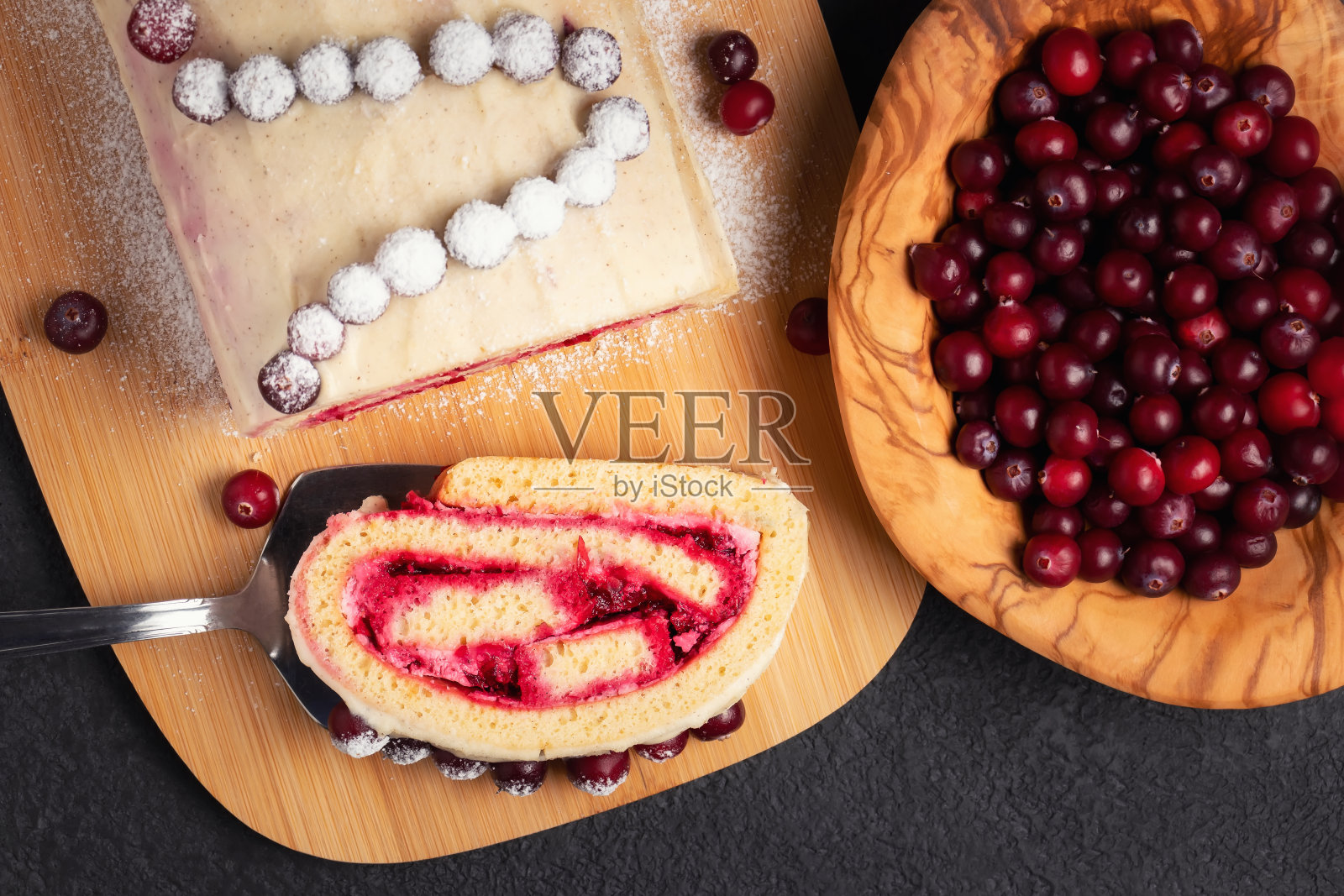 自制的小甜饼卷，配上蔓越莓和奶油，放在一张黑色的桌子上，俯视图，平铺照片摄影图片