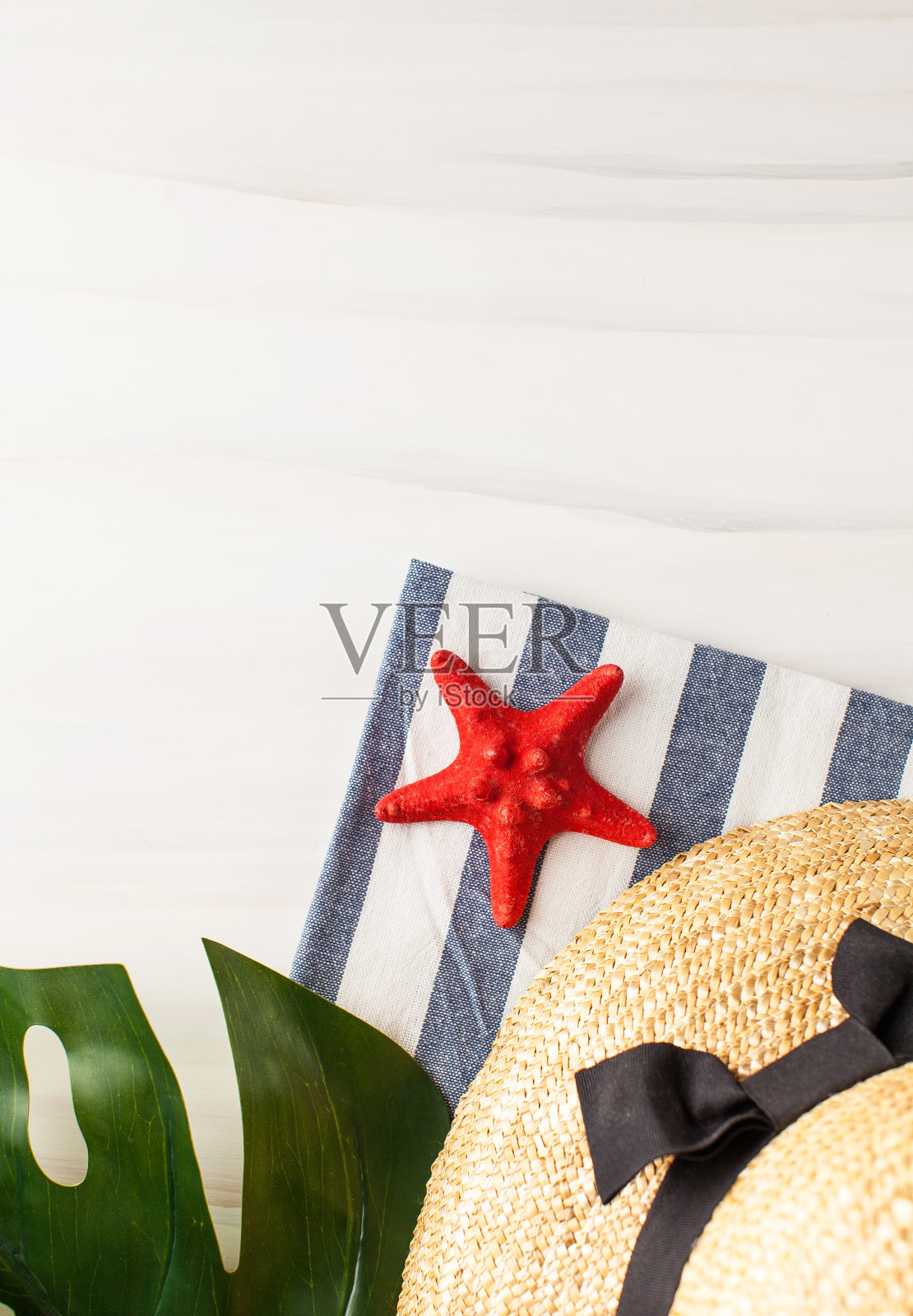 一顶草帽，一片绿叶和一只海星，背景很淡。夏天的背景。副本的空间。照片摄影图片