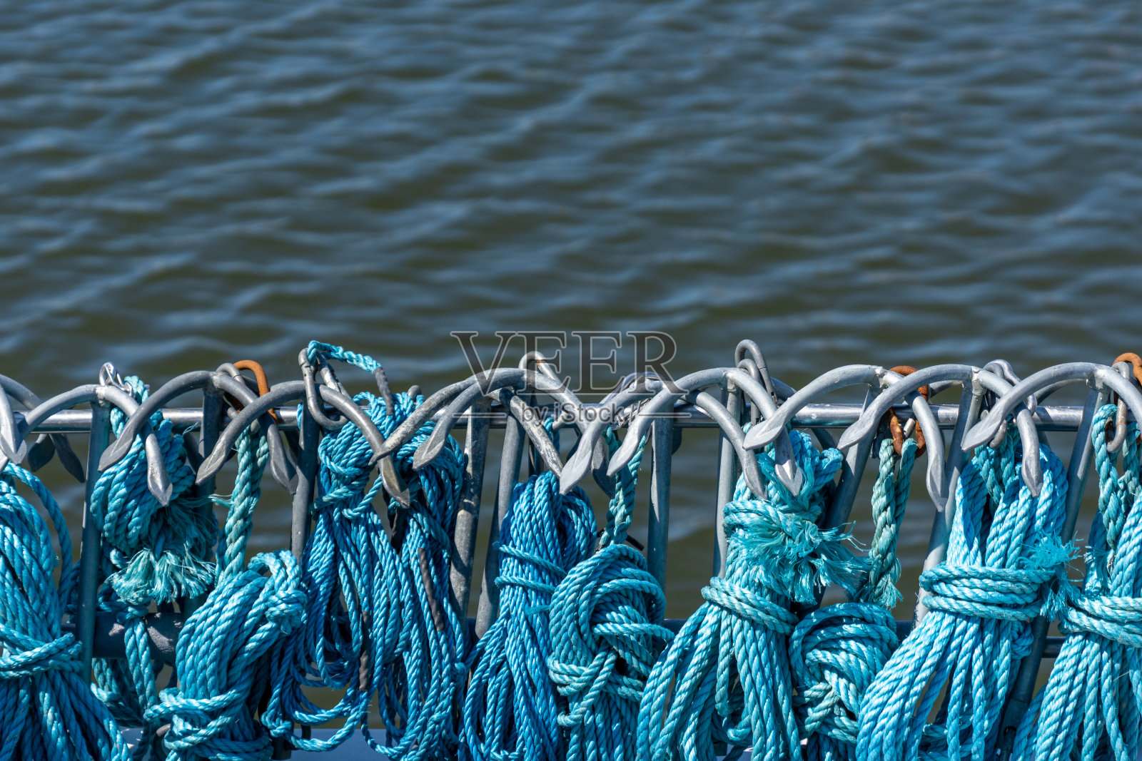 许多蓝色绳索和鱼钩的特写系在一艘渔船的栏杆上照片摄影图片