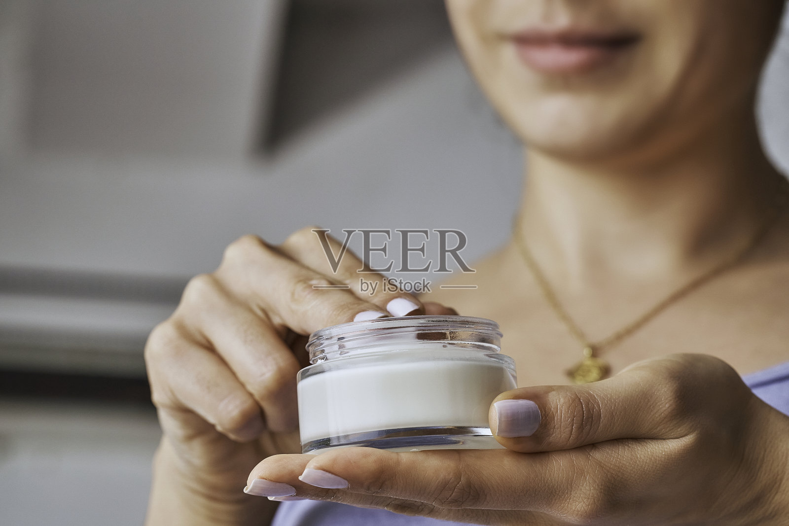 近距离观察年轻女子捧着一瓶保湿霜。美容的概念照片摄影图片