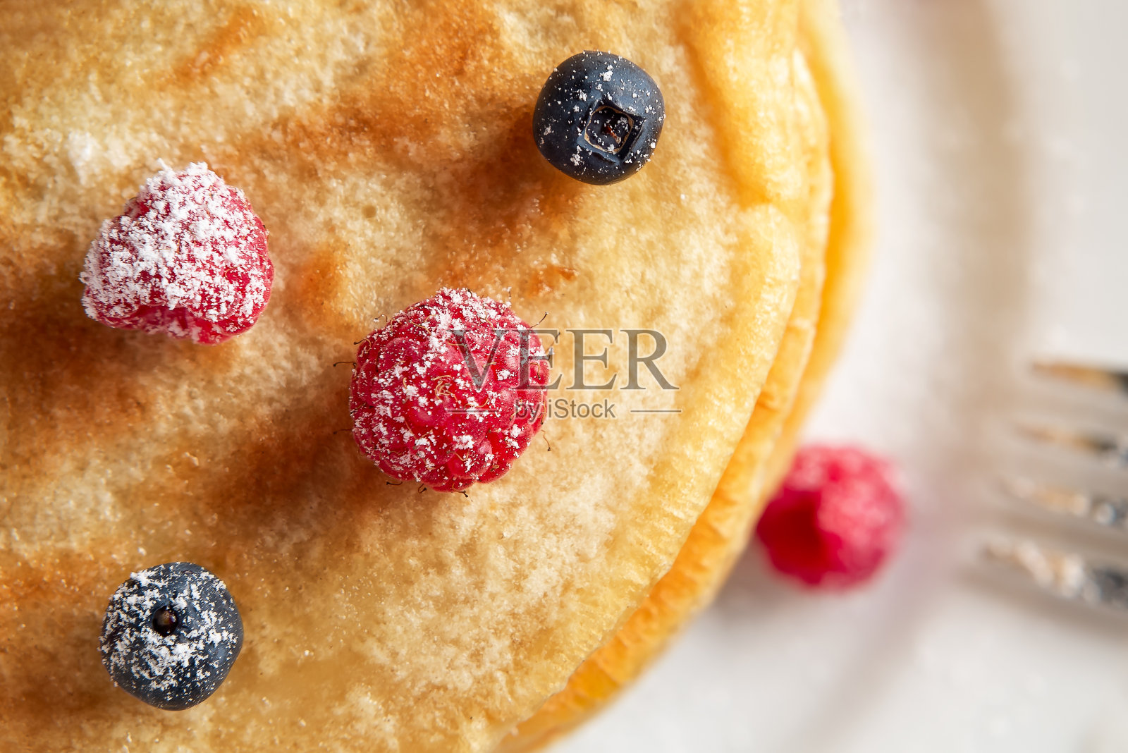 叠薄饼和新鲜的浆果在一个白色盘子上靠近，俯视图照片摄影图片