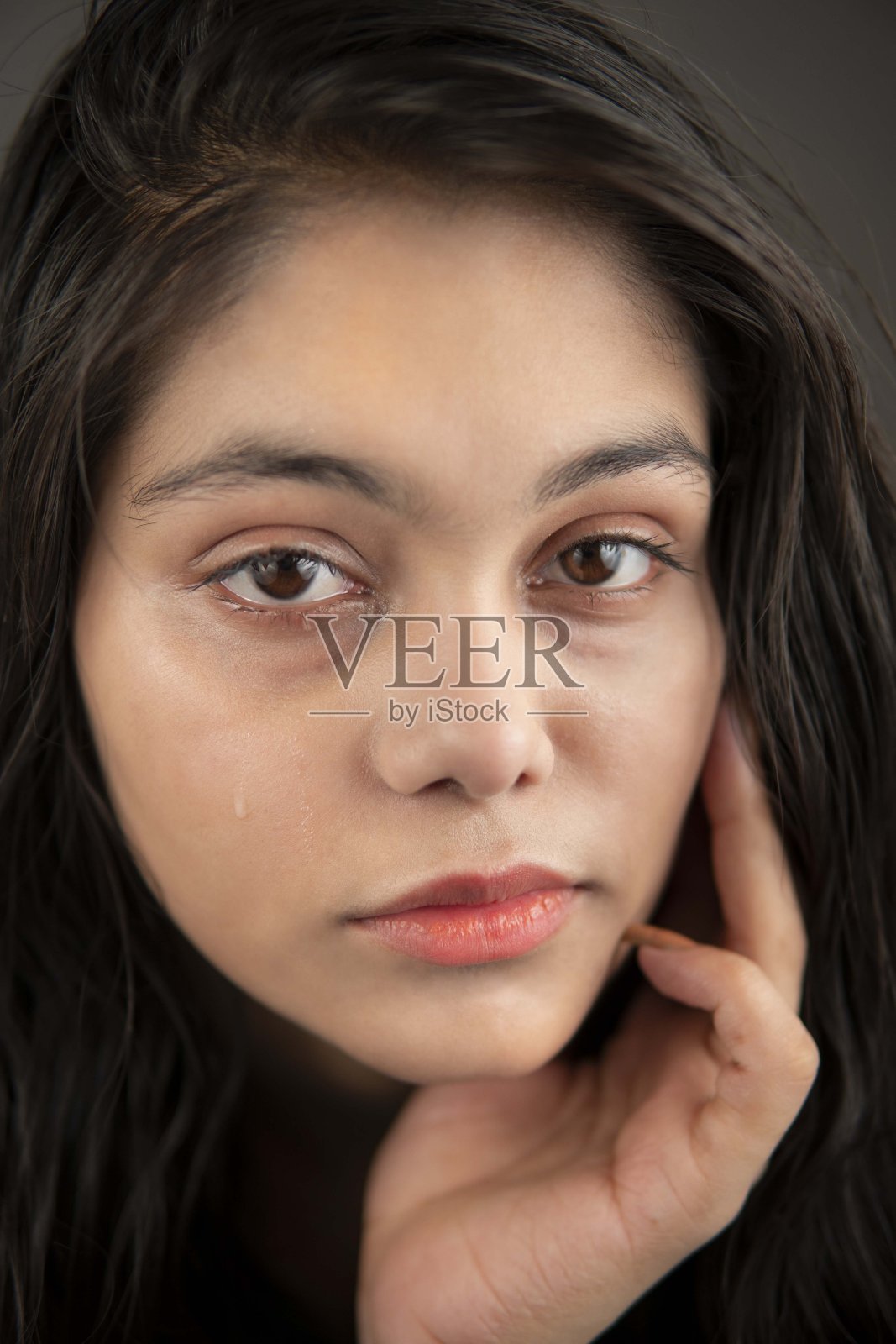 一个悲伤的印度女人看着镜头哭着流泪的肖像。照片摄影图片