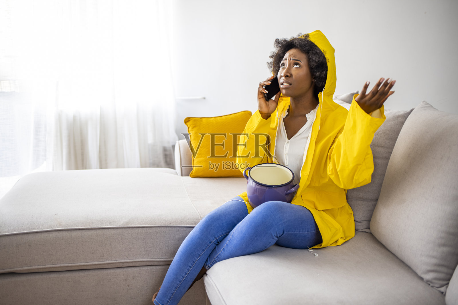 沮丧的房主坐在家里的沙发上看着天花板漏水。照片摄影图片