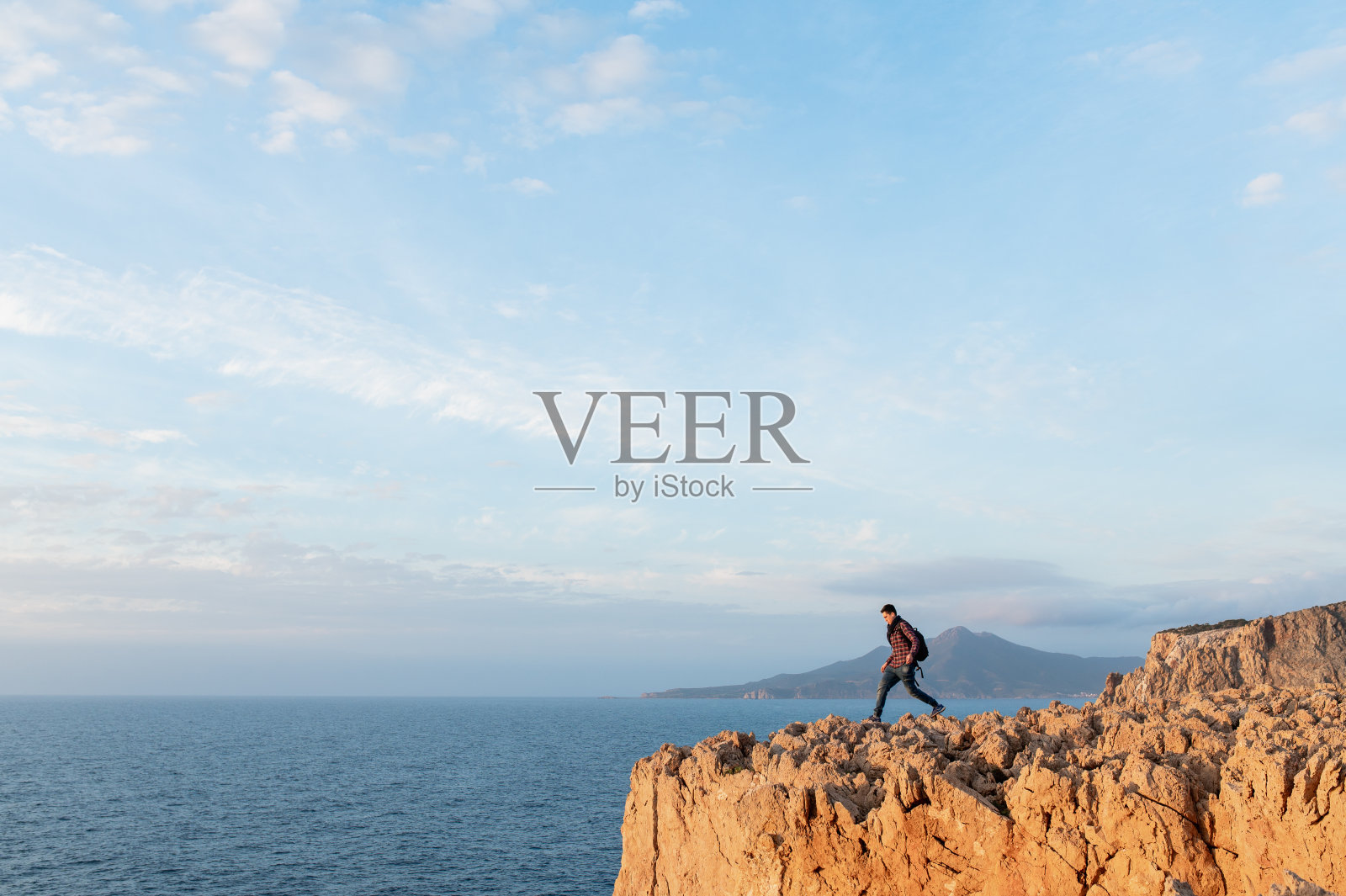 年轻徒步男子走在悬崖峭壁上照片摄影图片