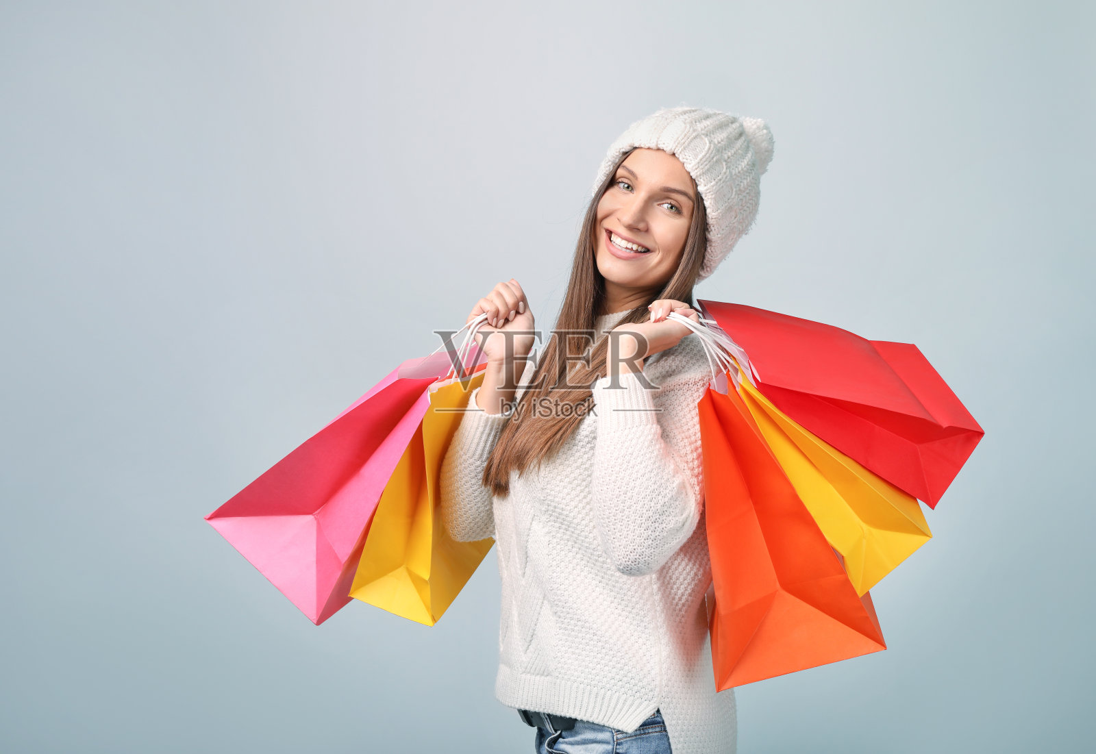 美丽的年轻女子购物袋在灰色的背景照片摄影图片