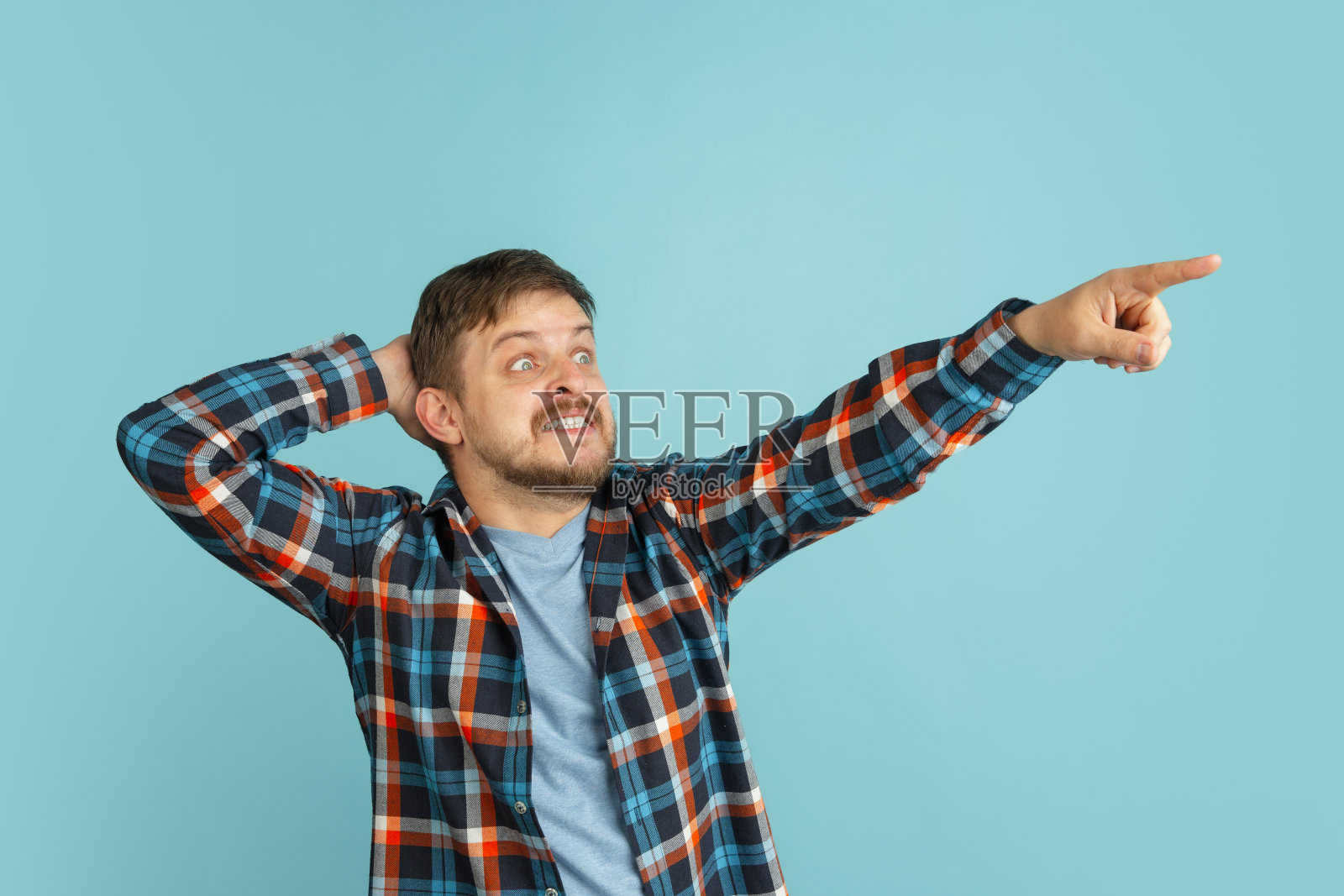 在浅蓝色背景中穿着休闲装的年轻白人络腮胡男子照片摄影图片