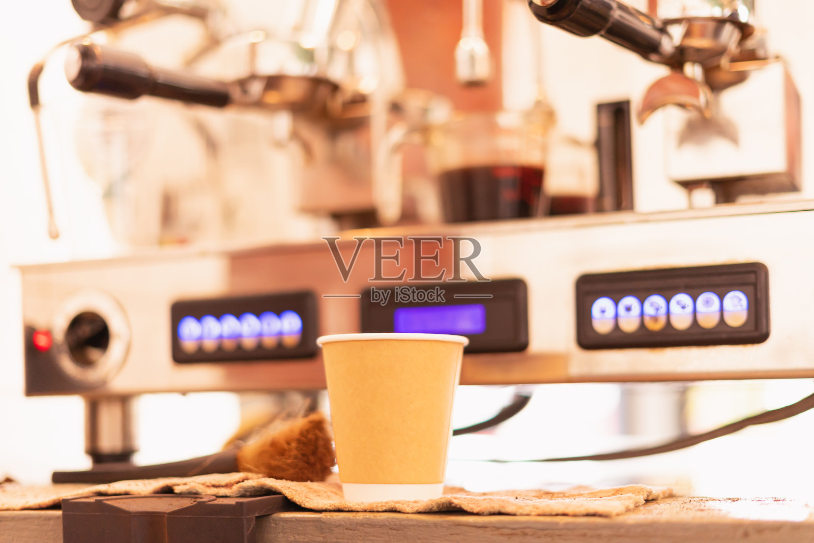 研磨机将黑咖啡磨成粉，然后流入咖啡吧的外卖咖啡杯。照片摄影图片