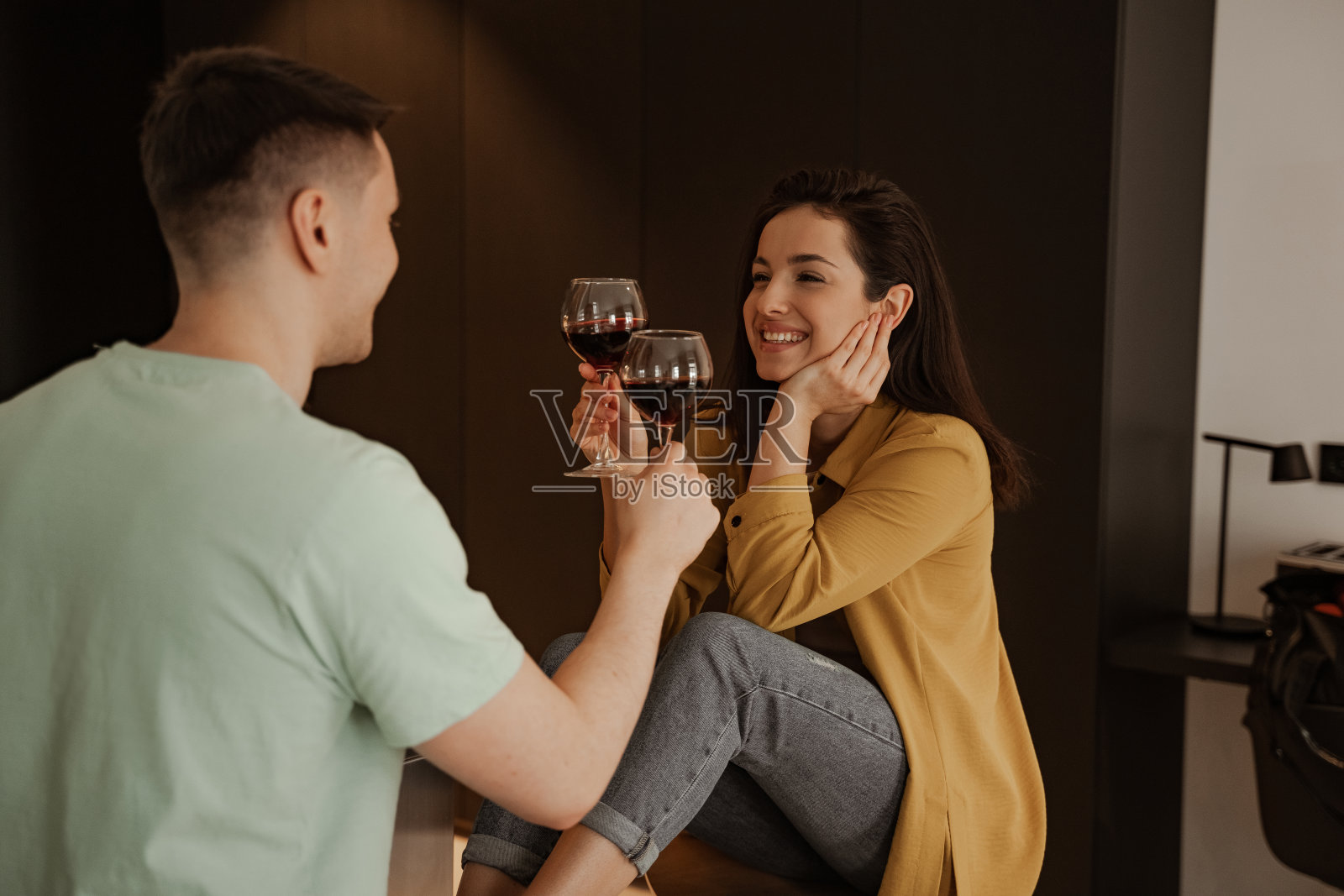 可爱的夫妇喝着葡萄酒在家享用浪漫的晚餐。幸福年轻的一家人搬到了新公寓照片摄影图片