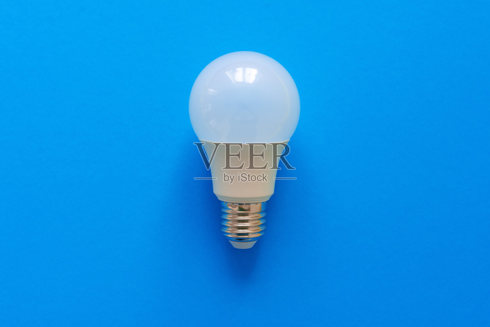 蓝纸背景上的一个灯泡照片摄影图片
