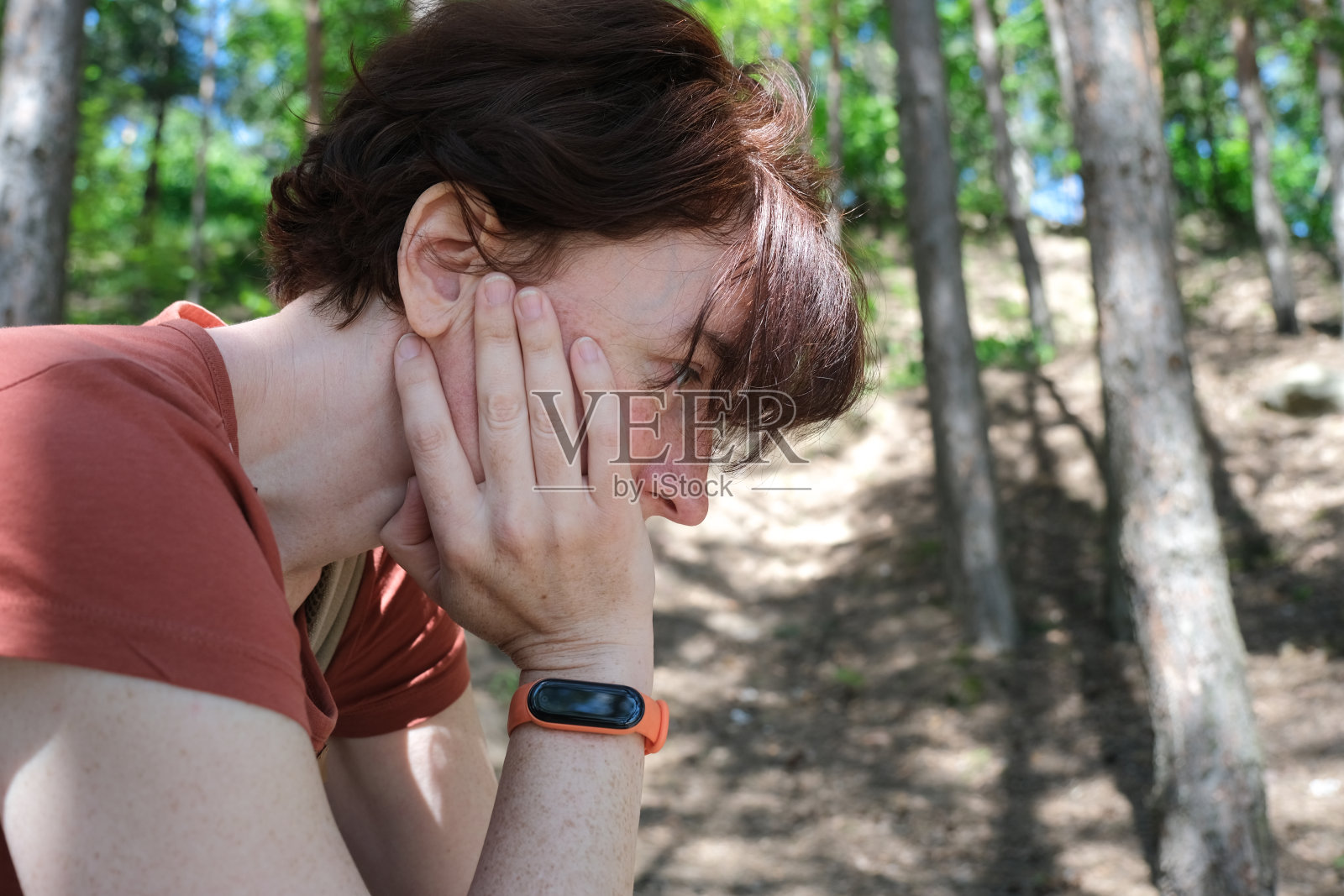 成熟的女人沮丧地坐在森林里照片摄影图片