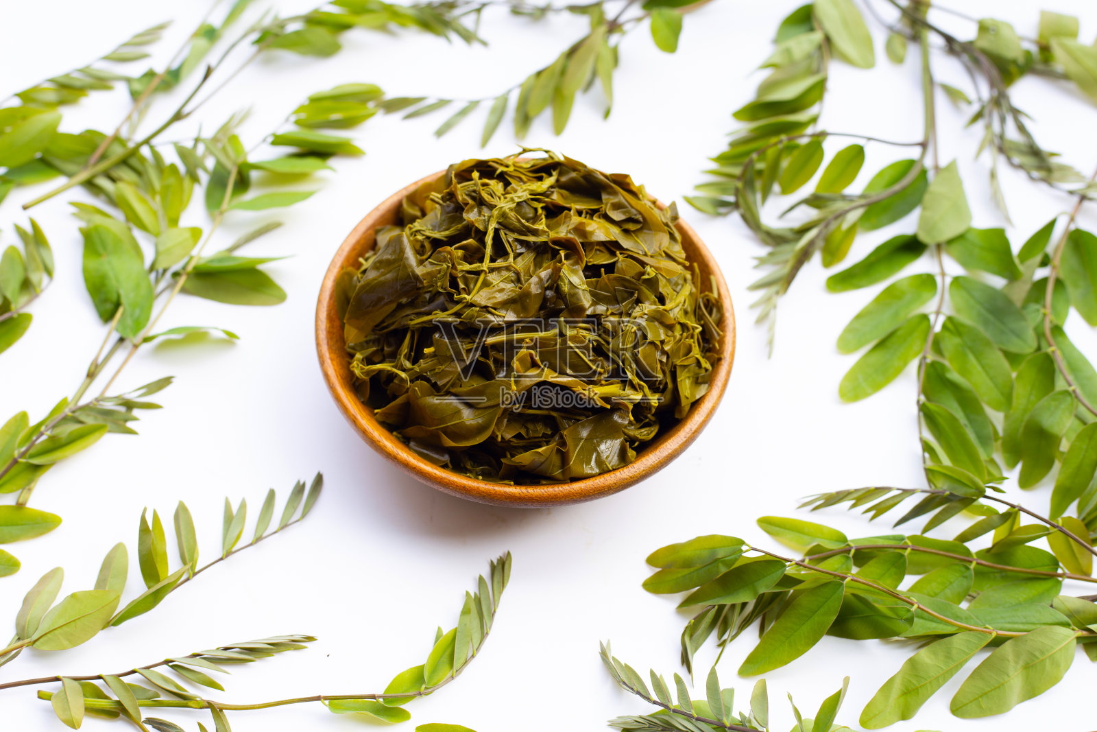 塞纳叶在木碗里煮熟，白色背景。照片摄影图片