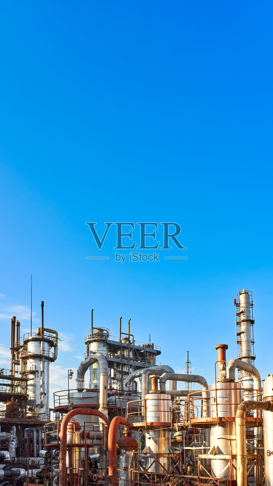 老蒸馏塔和反应器在蓝色的黄昏日落天空背景下化工厂。外部银色金属锈企业16x9垂直与copyspace。照片摄影图片