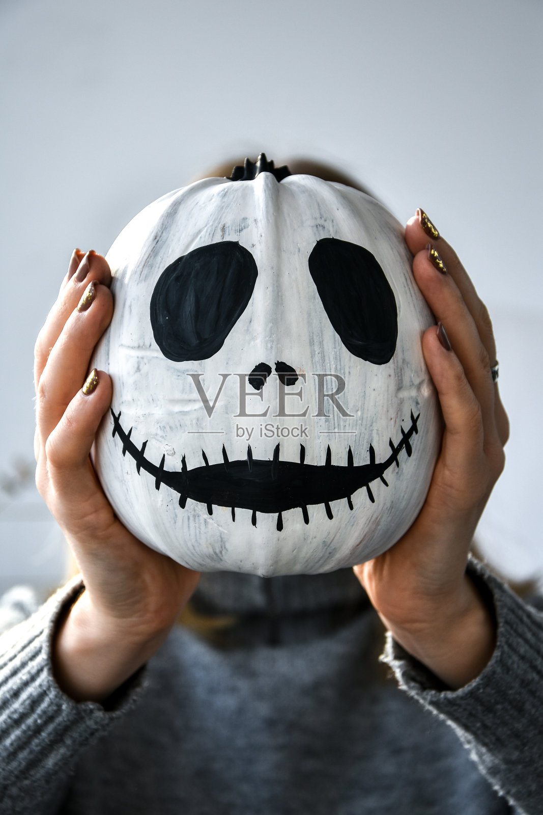 一个女人把滑稽的南瓜脸举在面前。万圣节背景Diy。自己动手照片摄影图片