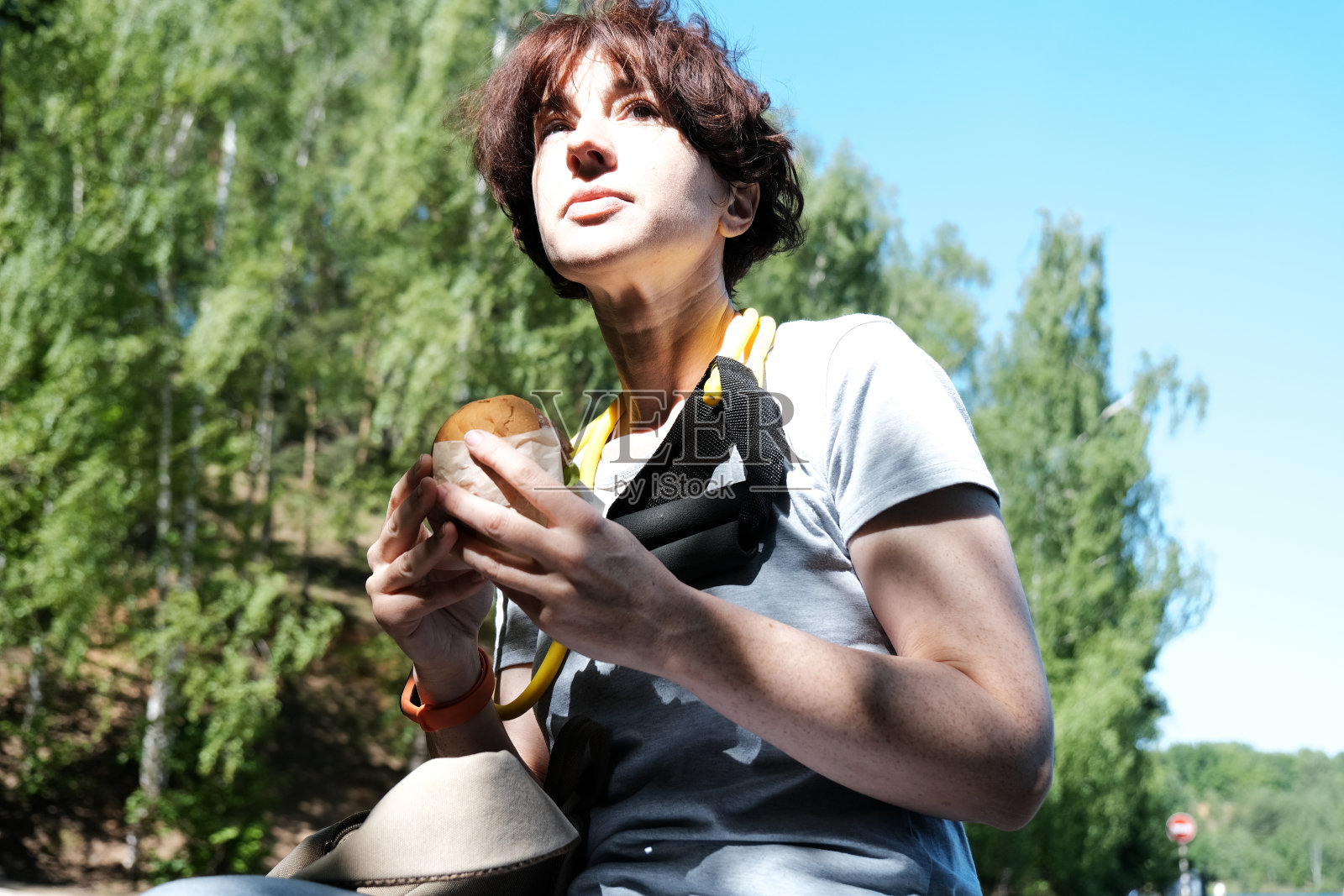 坐在湖边吃三明治的成熟女人照片摄影图片