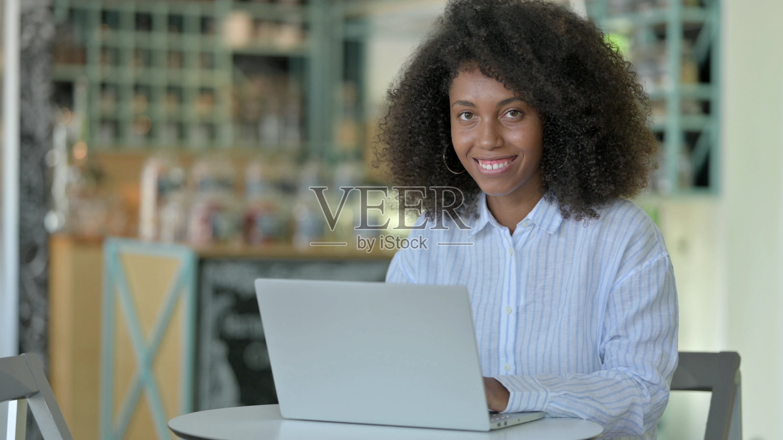 非洲妇女拿着笔记本电脑在咖啡馆里对着相机微笑照片摄影图片