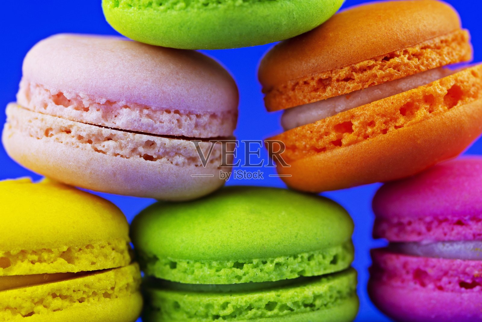 一堆彩色的马卡龙零食-蓝色的背景。照片摄影图片