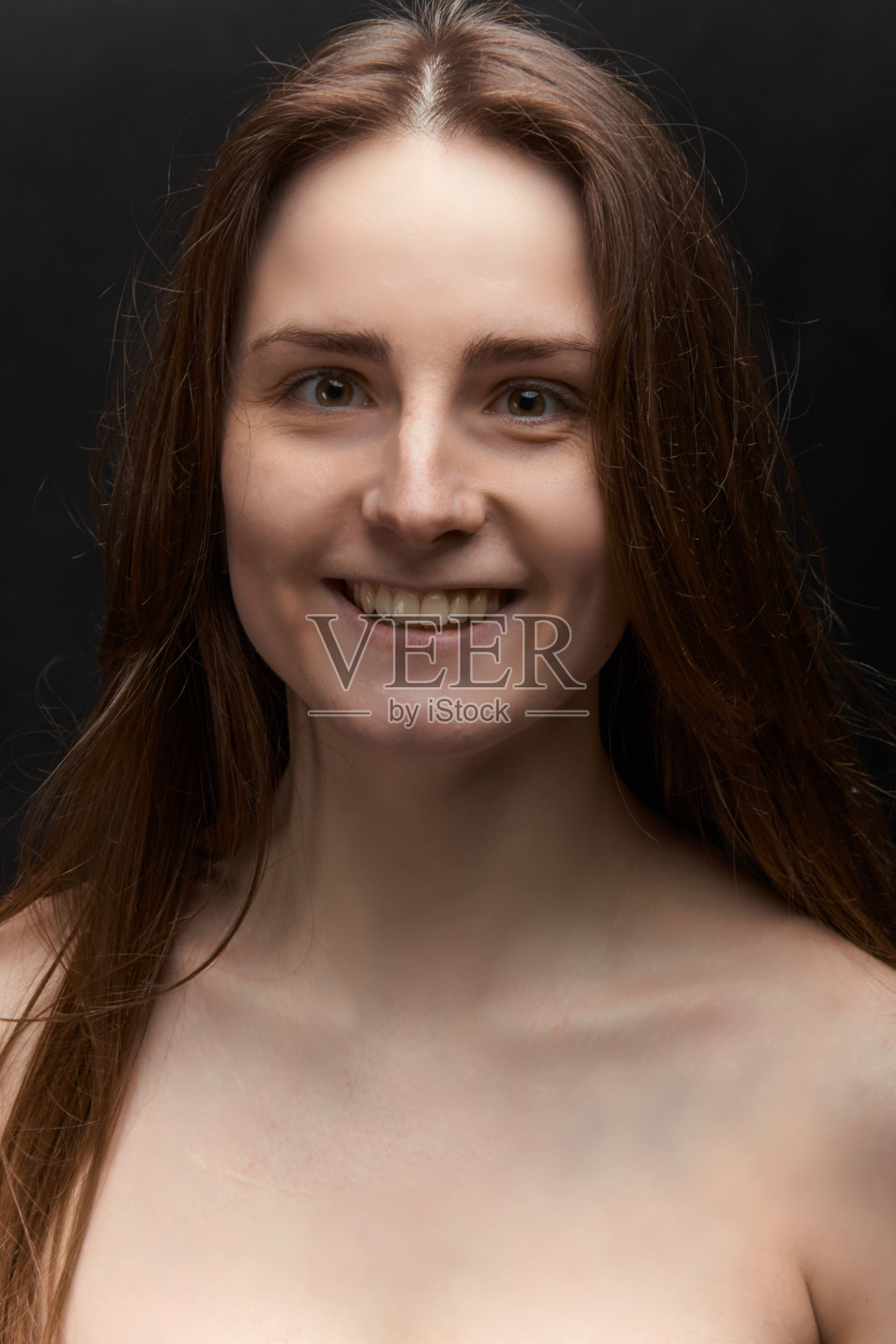 一个棕色长发的年轻女孩的肖像，在一个黑色的画室里照片摄影图片
