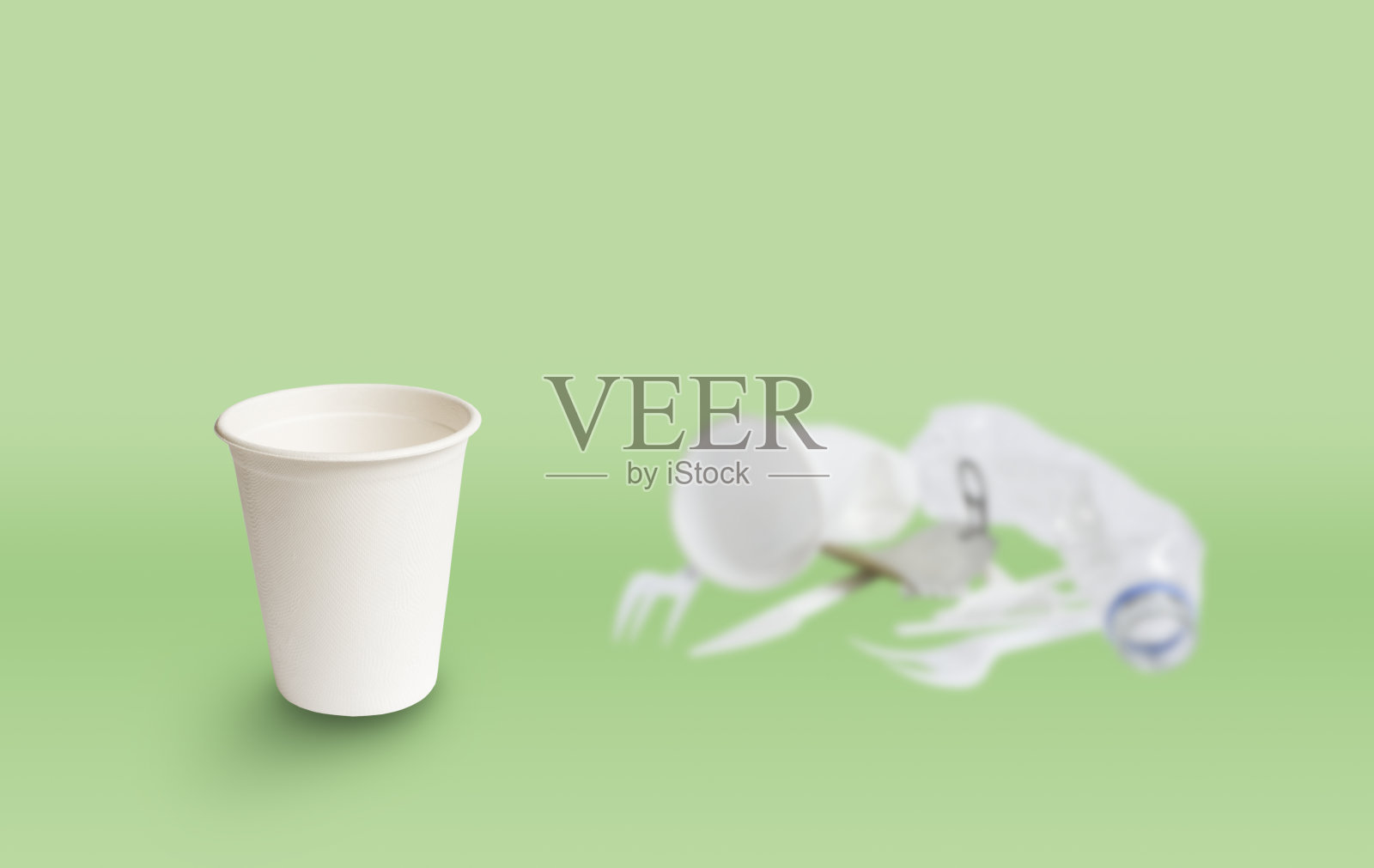 绿色背景上的环保纸玻璃。他身后是塑料碎片。选择生态菜的理念照片摄影图片