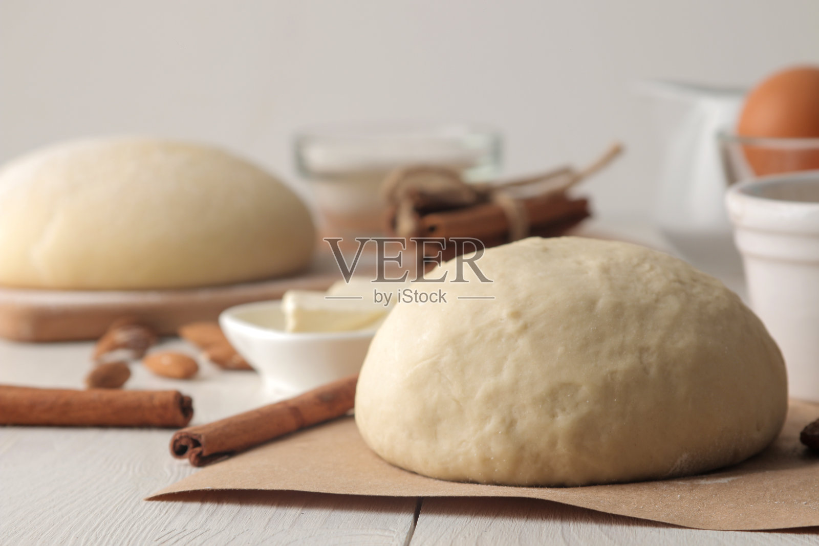 烘焙原料。面团特写和黄油，鸡蛋，糖，牛奶，肉桂，杏仁在白色的木制背景照片摄影图片