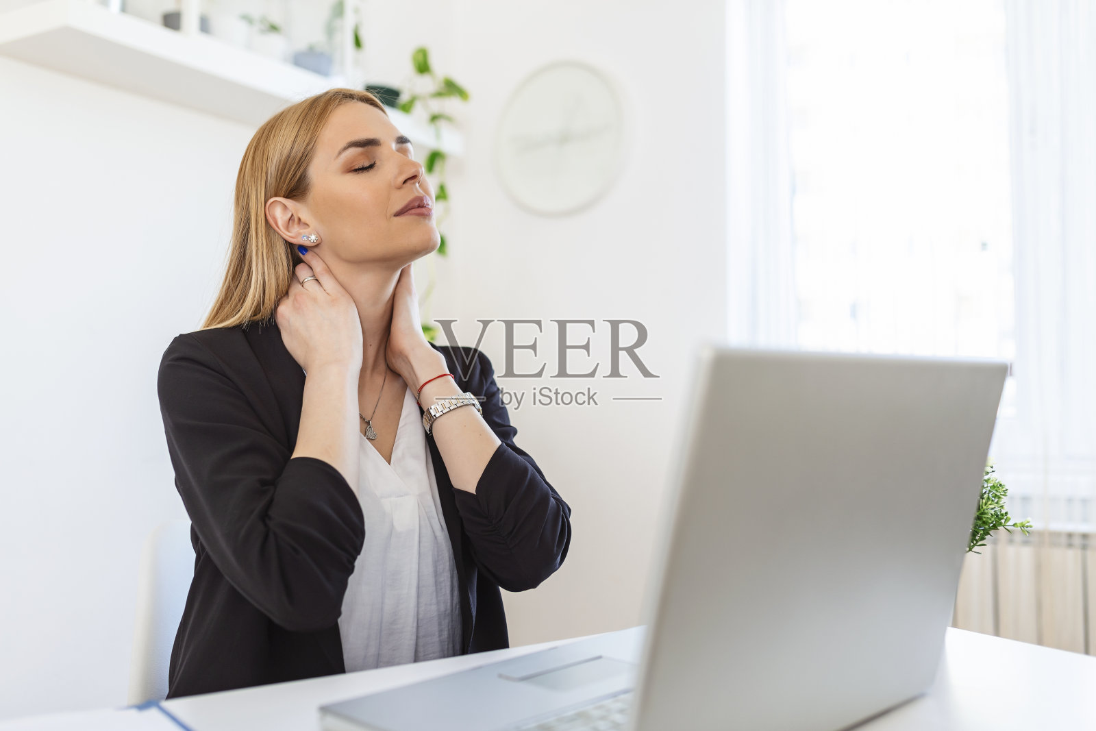 女商人觉得脖子痛后，坐在桌子上的笔记本电脑。因长时间在电脑上工作而患上“办公室综合症”的疲惫女性。漂亮女孩在按摩她紧张的颈部肌肉照片摄影图片