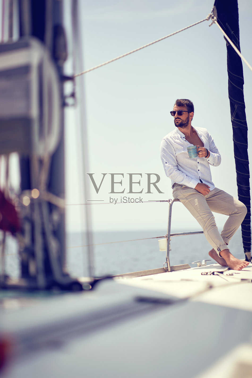 一位年轻英俊的男模正坐在海边的游艇上，享受着拍照的乐趣。夏天,大海,假期照片摄影图片