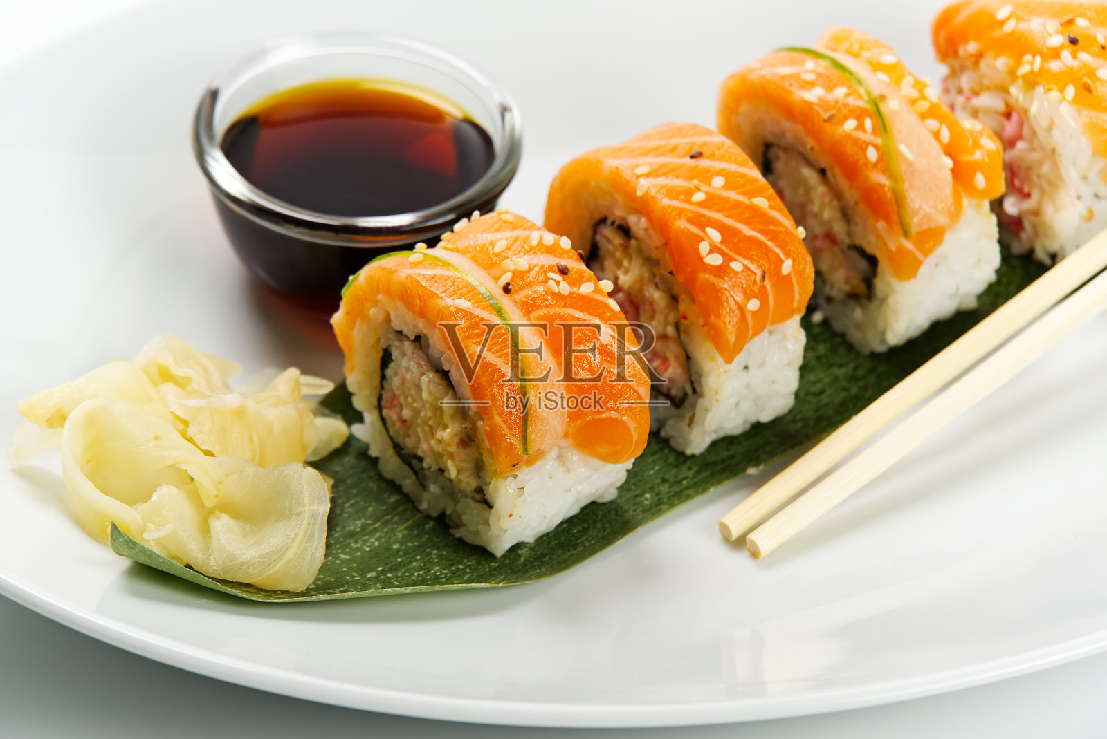 寿司和酱油在一个白色的碗和木筷子白色的桌子。日本的食物。日本海鲜寿司套装。寿司店的菜单上。照片摄影图片