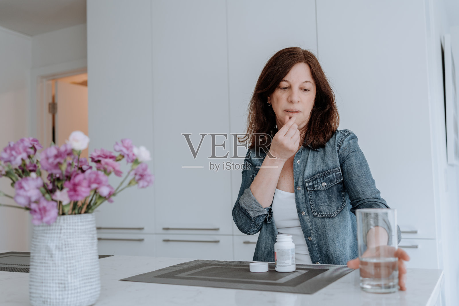 在厨房里吃维他命的女人照片摄影图片