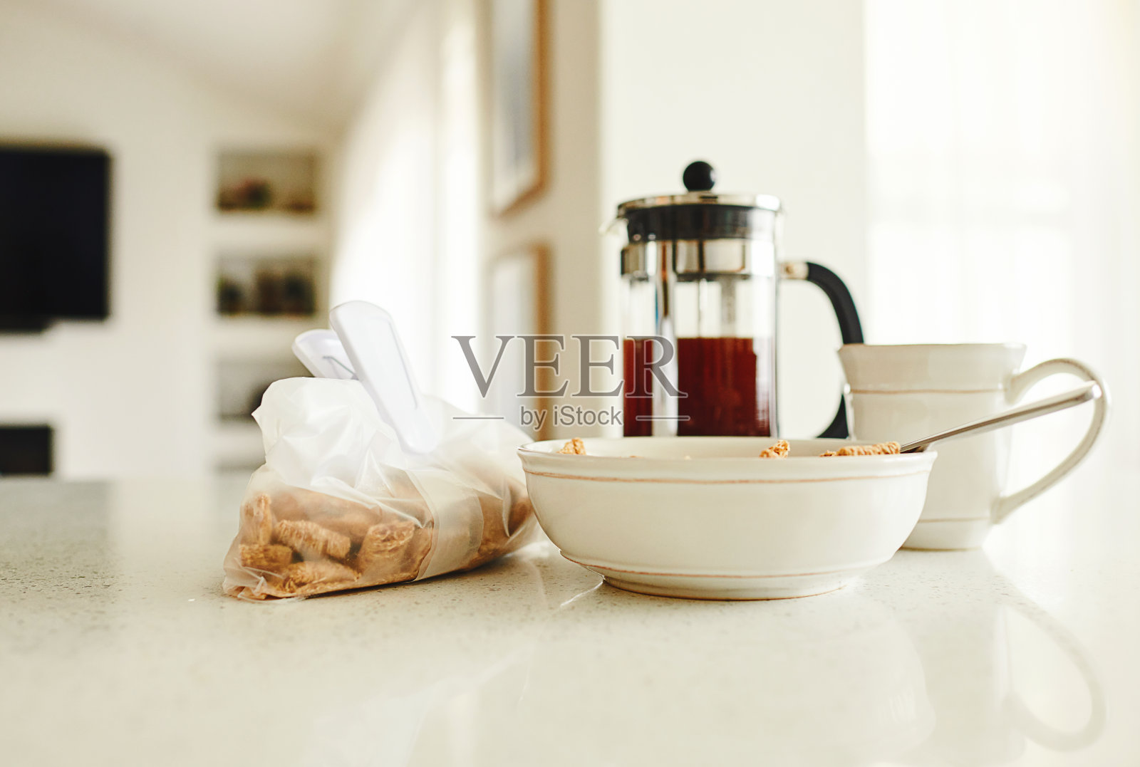 亮白色的厨房柜台上放着早餐碗和一袋麦片照片摄影图片