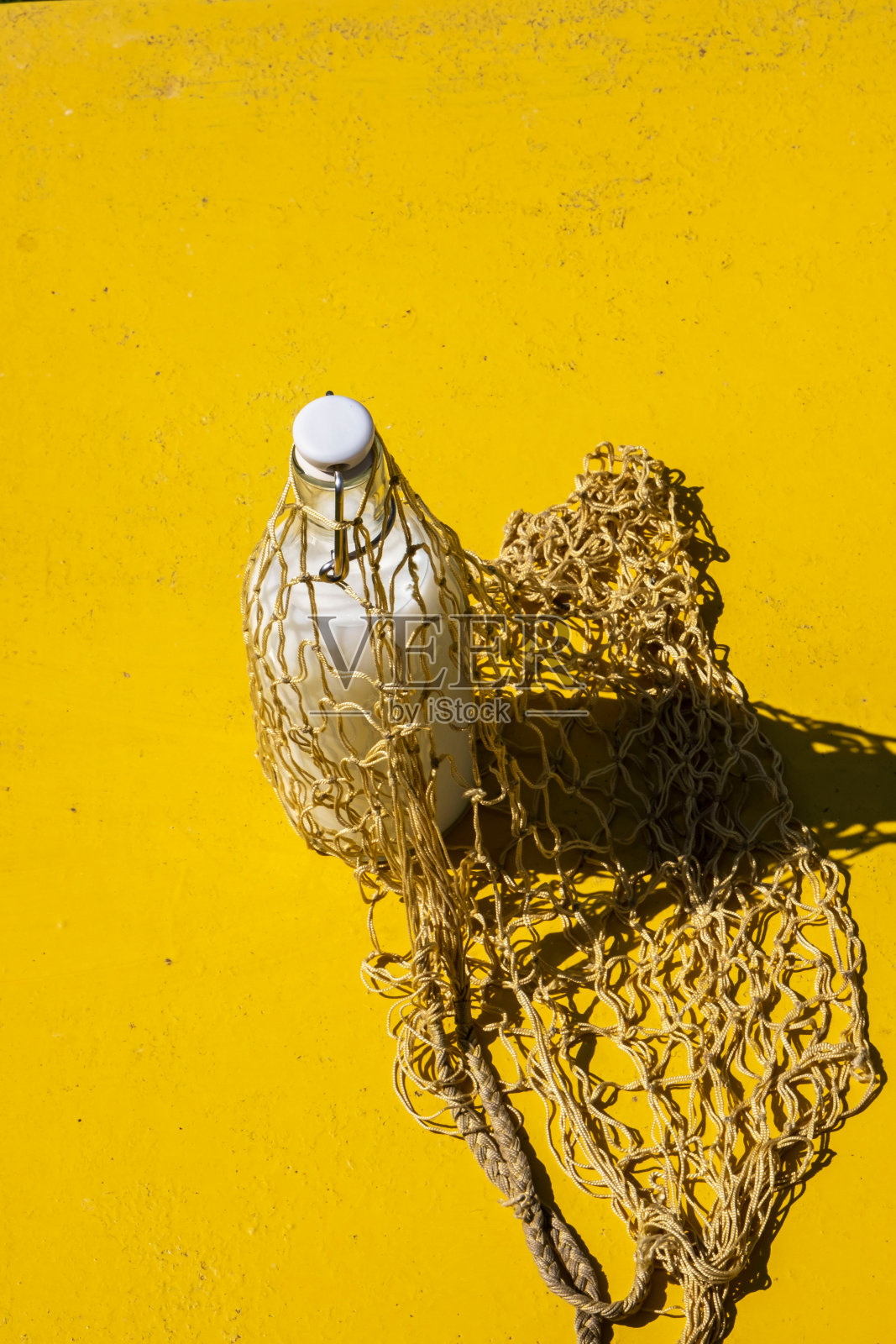 玻璃瓶牛奶在一个可重复使用的生态网购物袋，有坚硬的阴影。现代环保购物袋复古风格照片摄影图片