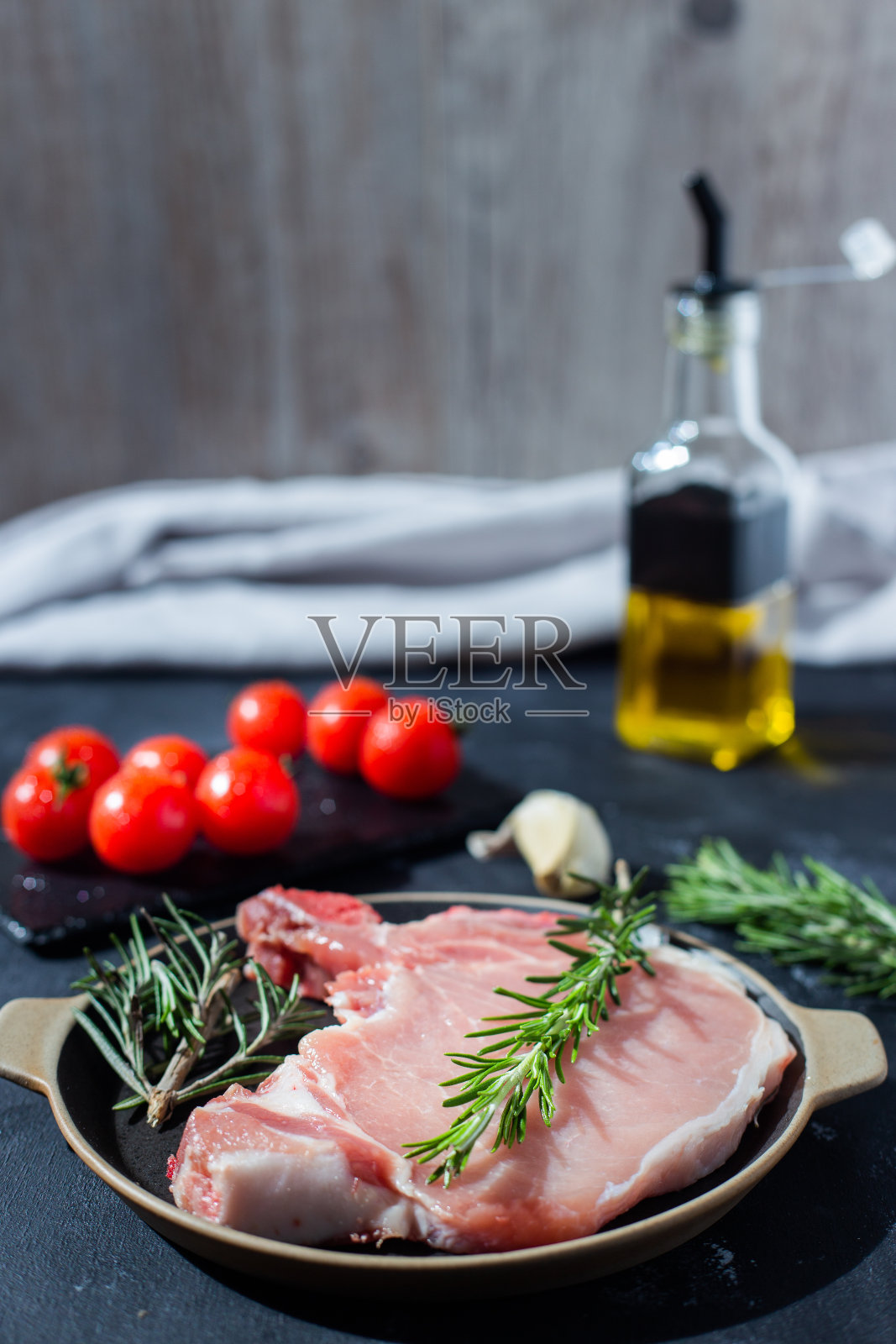 猪扒配樱桃番茄和其他配料，如迷迭香，大蒜，橄榄油。本空间照片摄影图片
