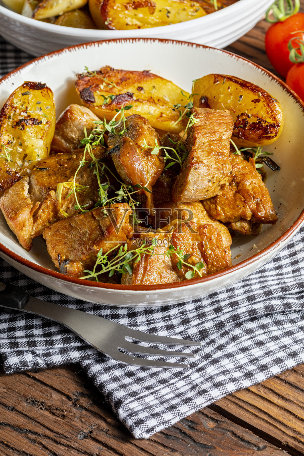 开胃炖猪里脊肉在锅中煮熟，切成小方块。配以烤土豆、大蒜、盐、牛至和新鲜番茄。自制的看。特写镜头照片摄影图片