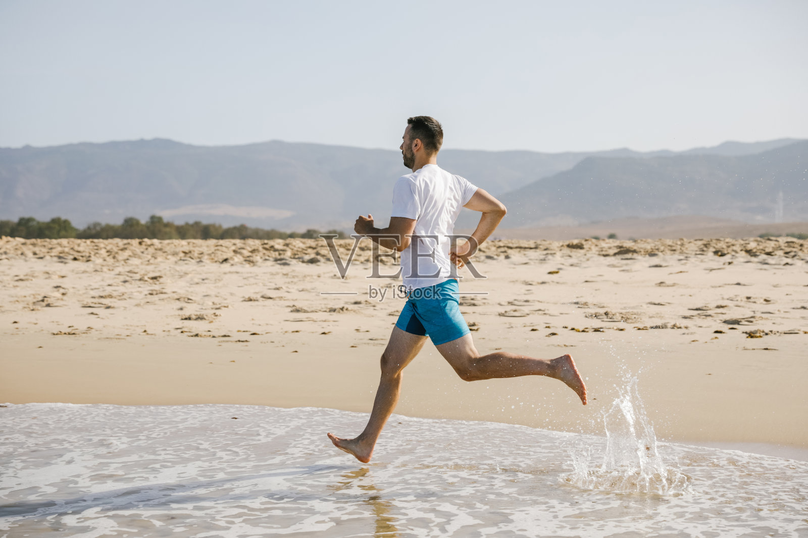 一个年轻人在海滩上跑步照片摄影图片
