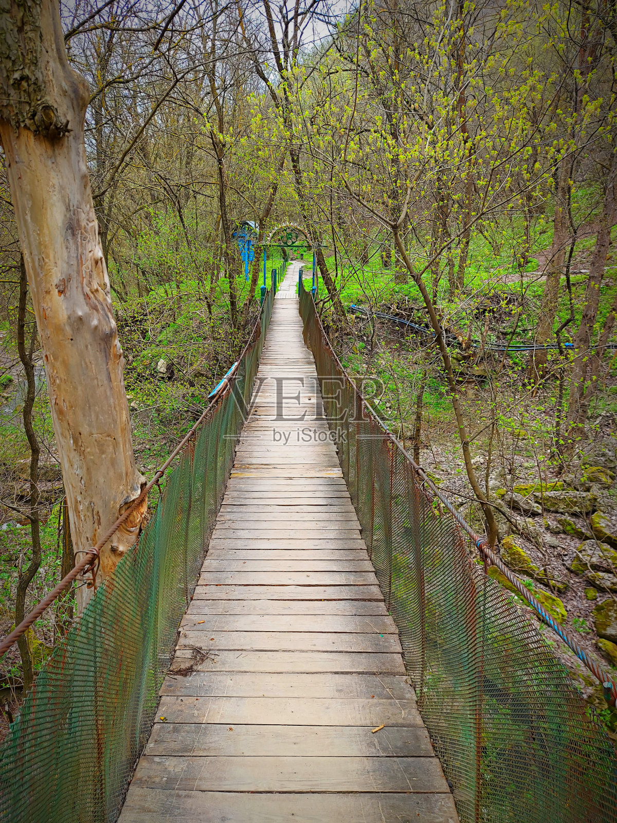 小而古老的木桥在山上的河流上状况良好。美丽的山景有干燥的树木和覆盖着绿色草地的土地。一个人在大自然中。照片摄影图片