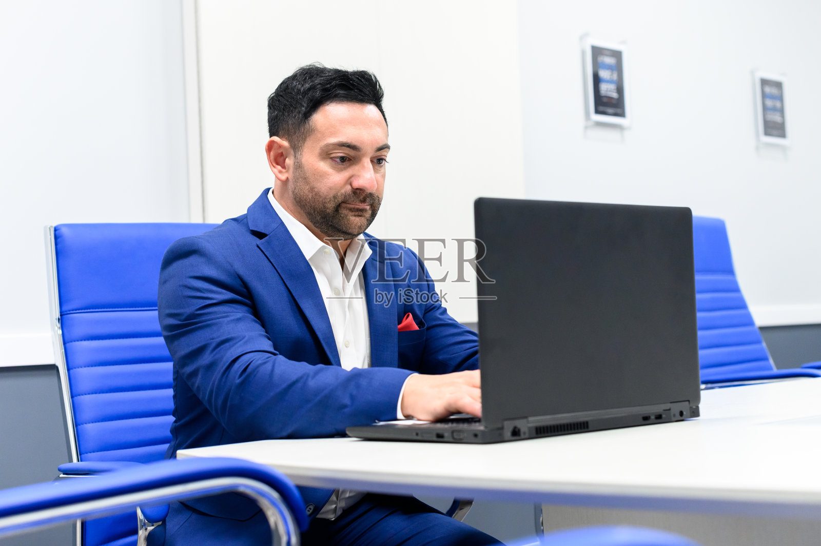 一名男子在一间空荡荡的现代会议室里用笔记本电脑工作照片摄影图片