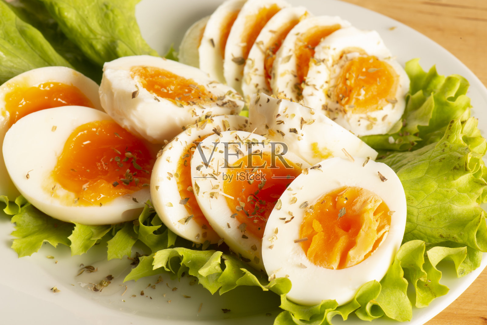 白盘子里的生菜上放着煮蛋和香料照片摄影图片