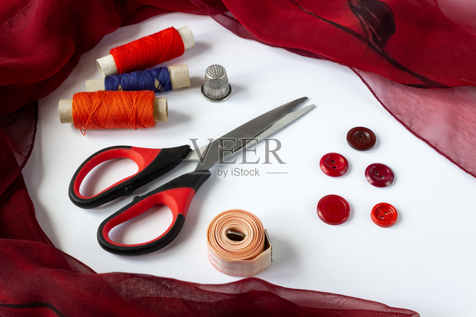 缝纫配件:线圈、纽扣、顶针、剪刀和白色背景上的厘米。照片摄影图片