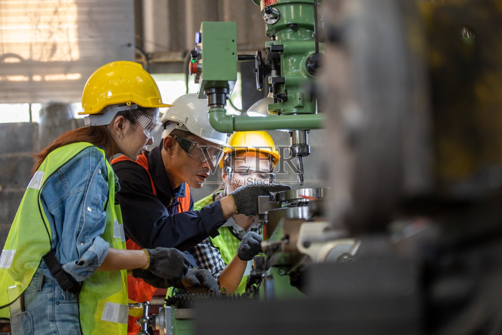 亚洲集团工业经理男示范和培训机械工人女操作工业车床。工业工程人技术理念。照片摄影图片