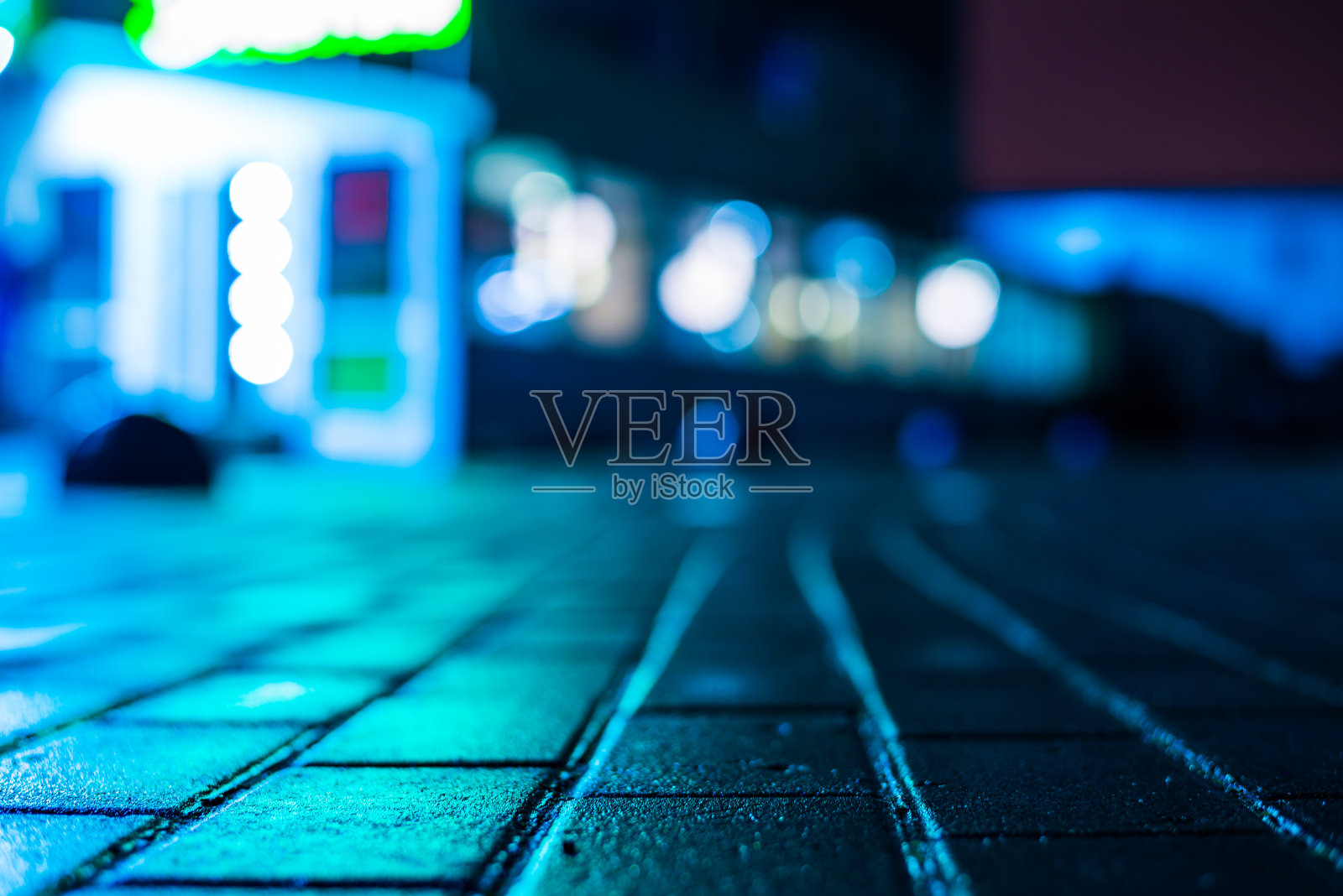 城市的雨夜。商场的入口。潮湿的人行道上商店橱窗的倒影。五彩缤纷的颜色。照片摄影图片