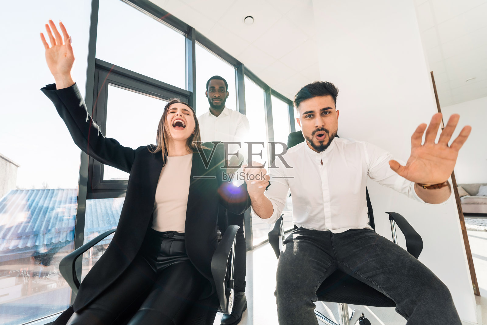 年轻的多种族商人在椅子上玩疯狂的办公室游戏照片摄影图片