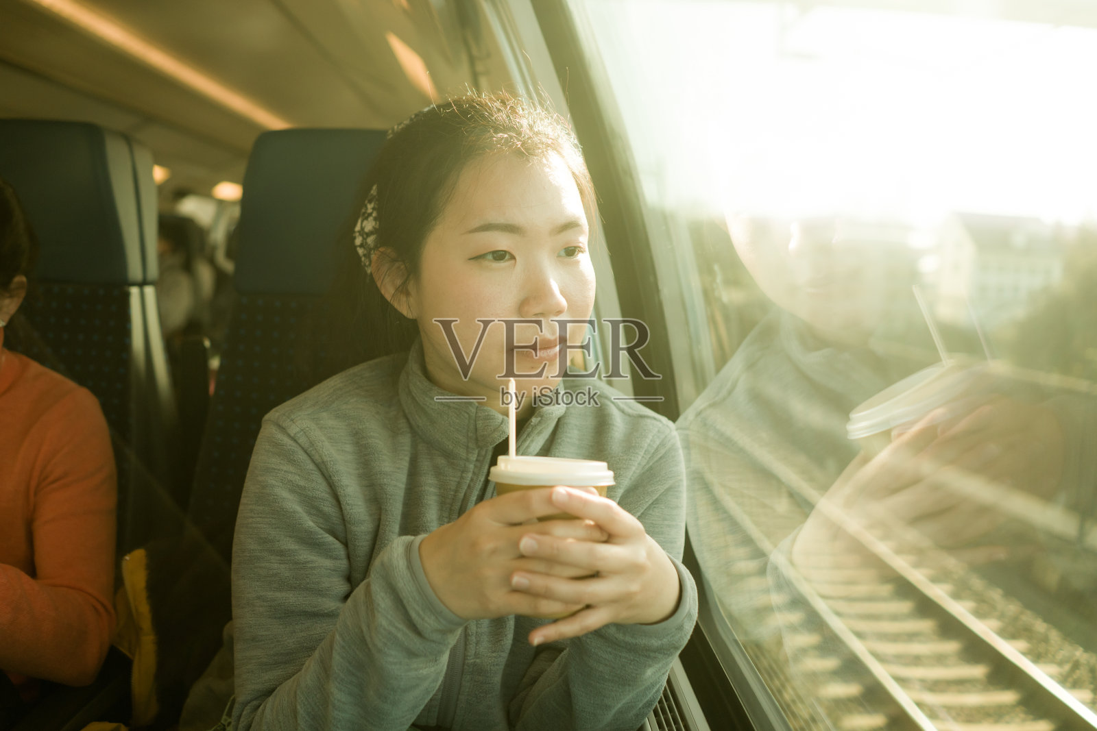 火车旅行-生活方式的肖像，年轻快乐和美丽的亚洲韩国女人在火车上透过窗户看照片摄影图片