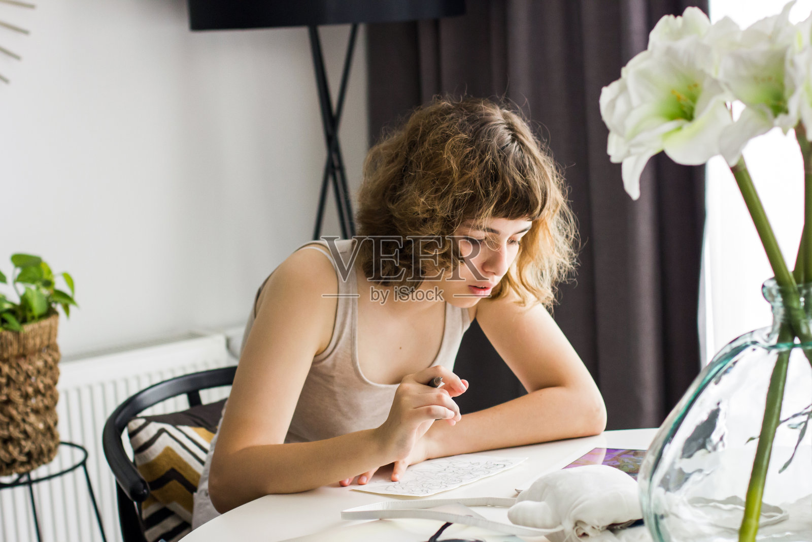 年轻女孩在白色的桌子上做作业。家庭教育和家庭教育照片摄影图片