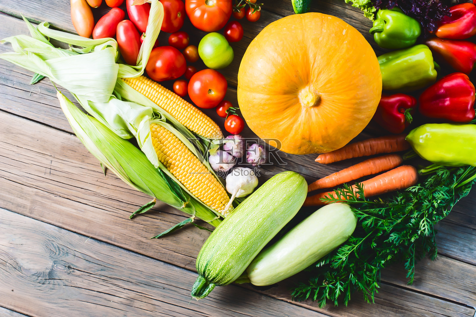 蔬菜的丰收。蔬菜(胡萝卜、玉米、黄瓜、番茄、洋葱、大蒜、玉米、辣椒等)摆放在一个木制的背景上。健康天然的食品。照片摄影图片