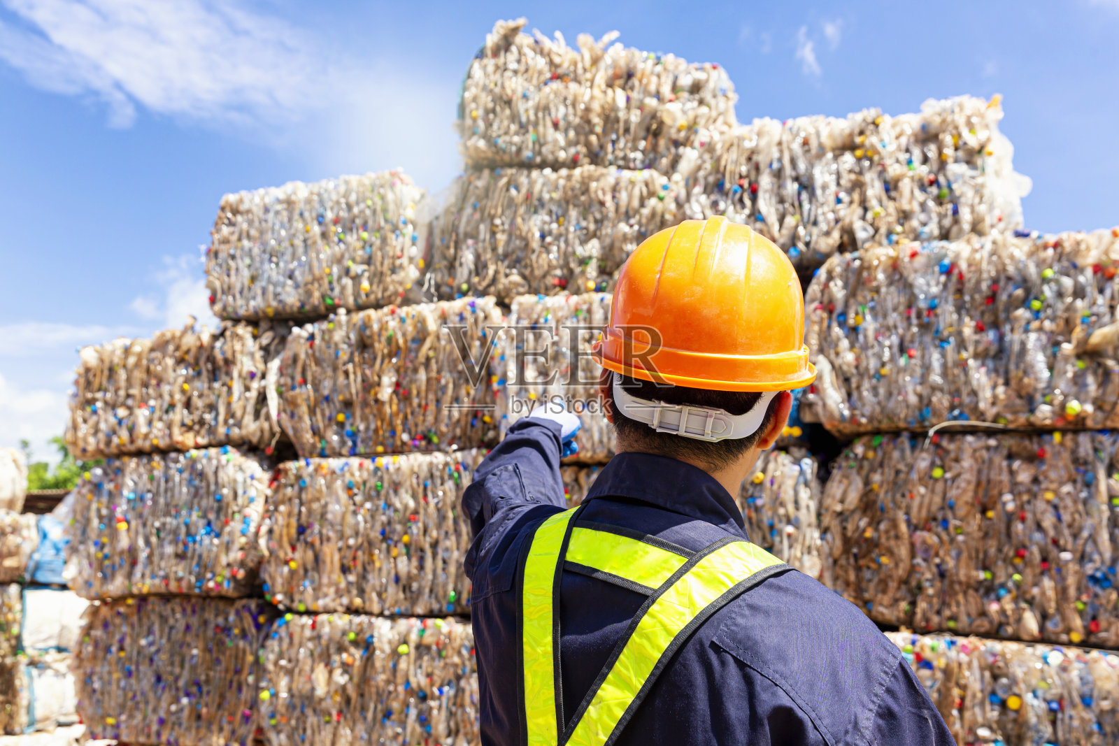 回收工厂的一名员工指出，塑料垃圾正在被送往回收过程。照片摄影图片