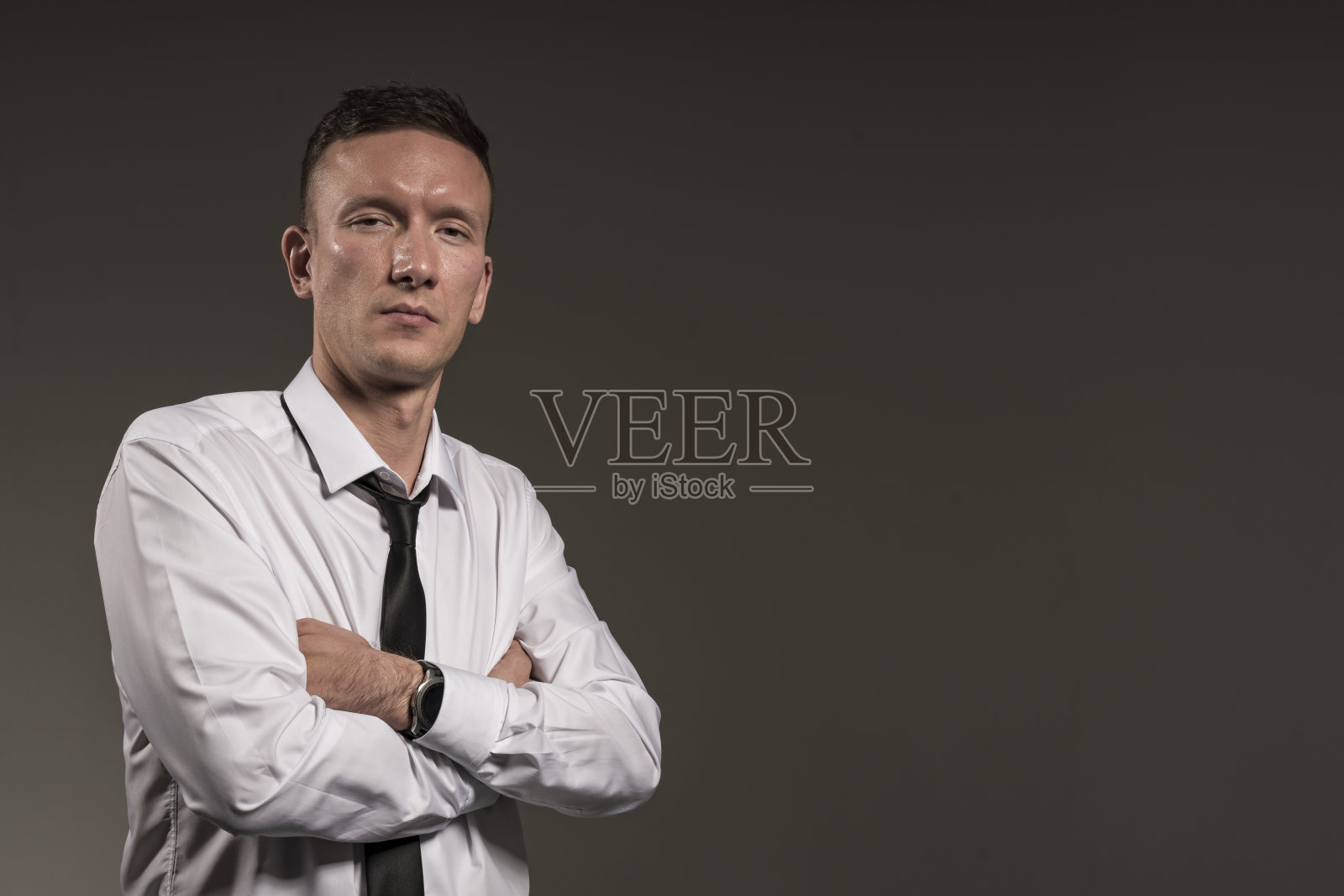 穿衬衫打领带的办公室职员。一个穿着白衬衫的年轻人的肖像，背景是黑色的。照片摄影图片