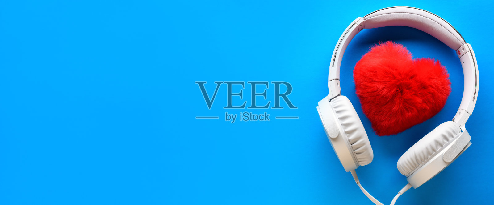 白色有线耳机和红色的心在蓝色的背景。娱乐的概念。横幅照片摄影图片