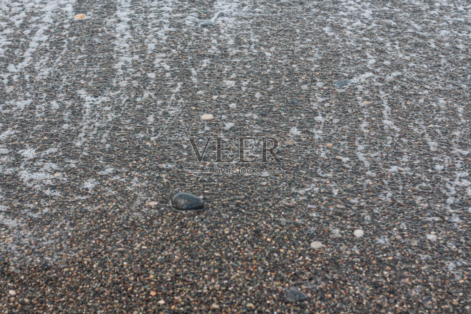 海滩石头鹅卵石潮湿的背景与可见的白色痕迹的海浪照片摄影图片