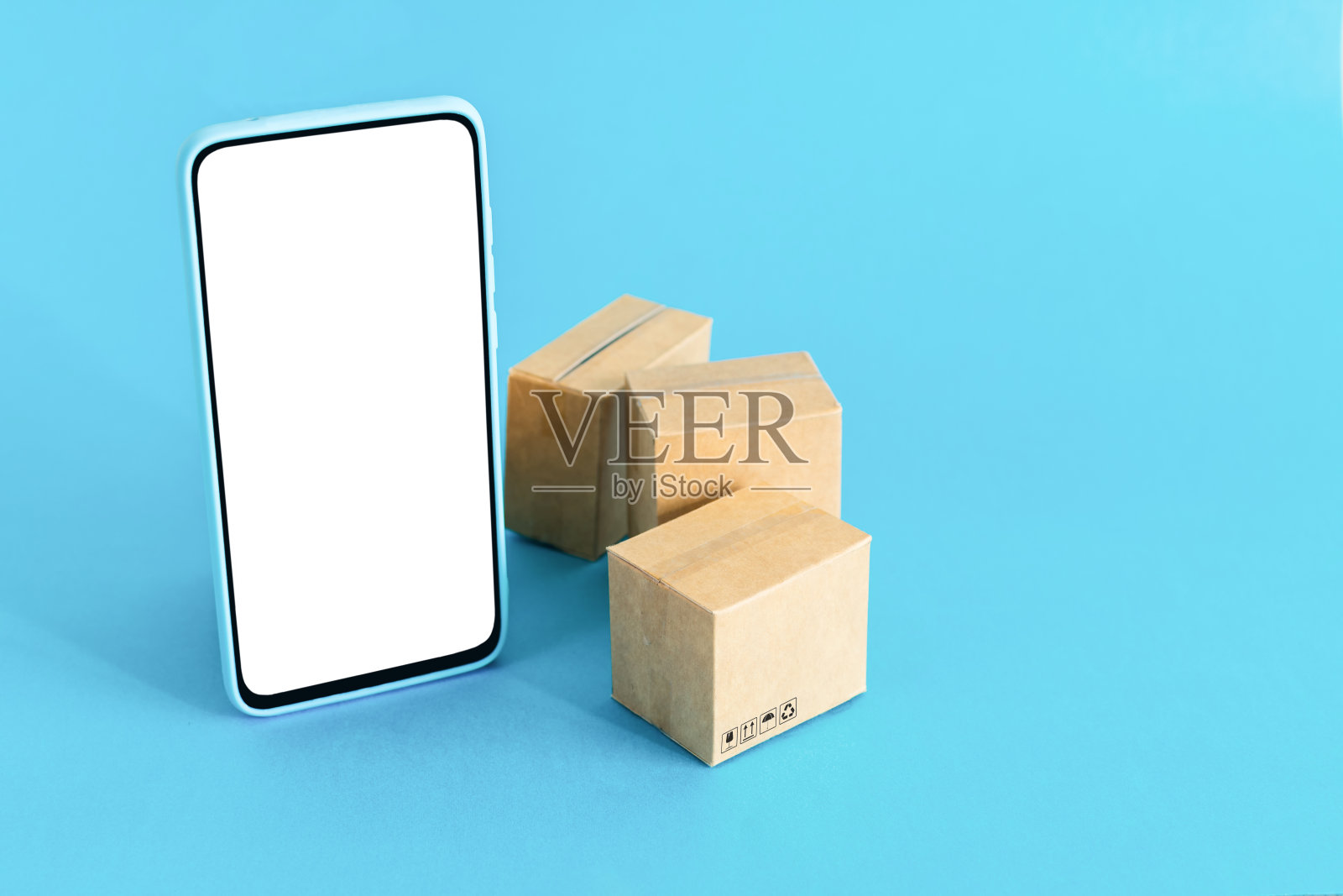浅蓝色背景上带空白屏幕和纸板箱的智能手机：在线购物和配送服务概念照片摄影图片