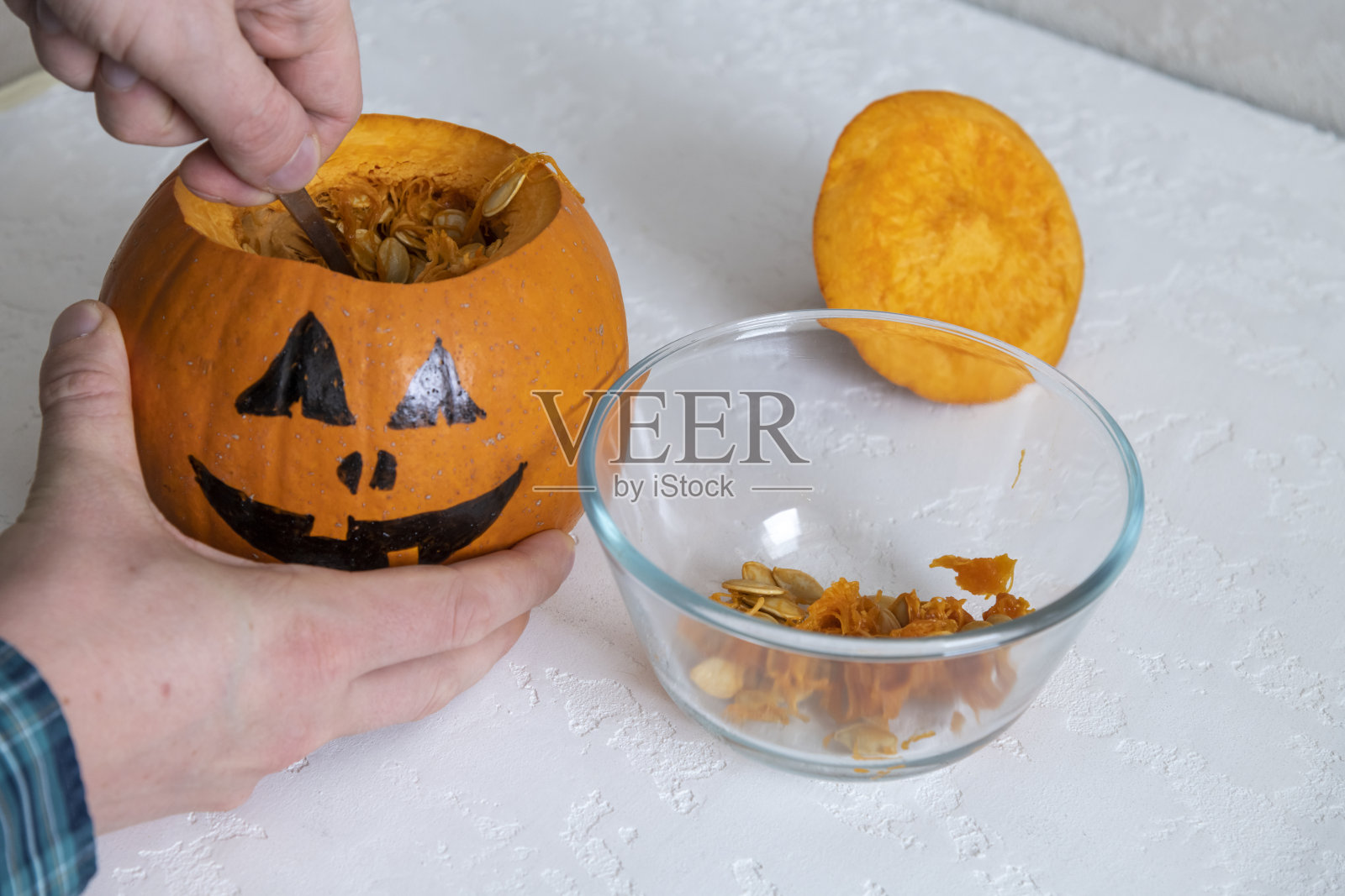 人从万圣节南瓜上取下种子照片摄影图片